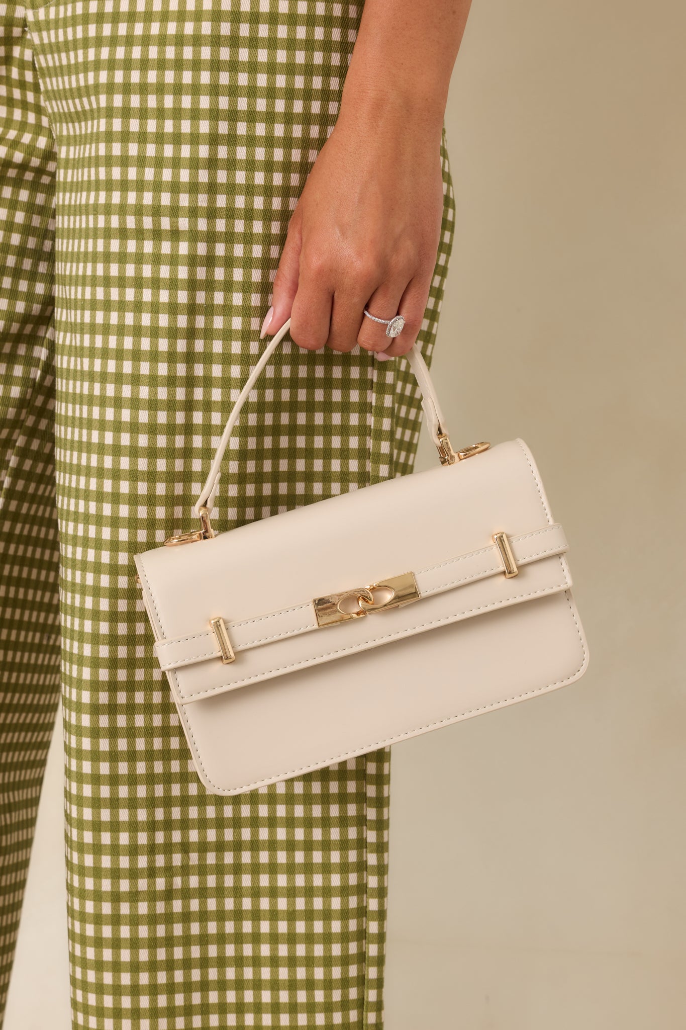 Front belt detail with interlocking accent adds a sophisticated touch to this structured faux leather handbag.