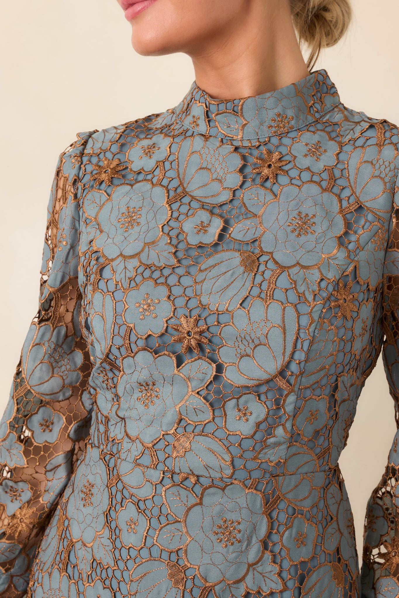 Close-up of the dress's intricate floral lace overlay, revealing delicate botanical motifs and bronze-toned detailing.