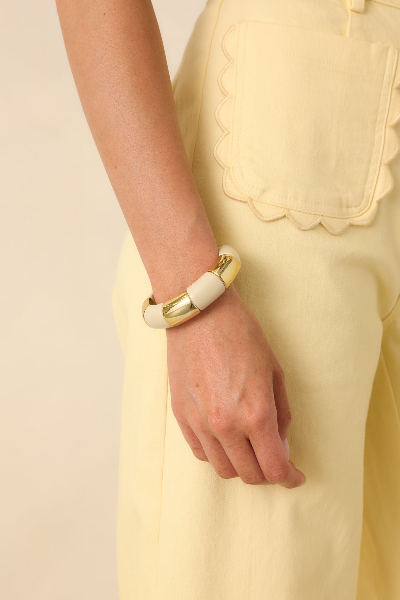 Cropped view of ivory and gold statement bracelet featuring alternating smooth beads.