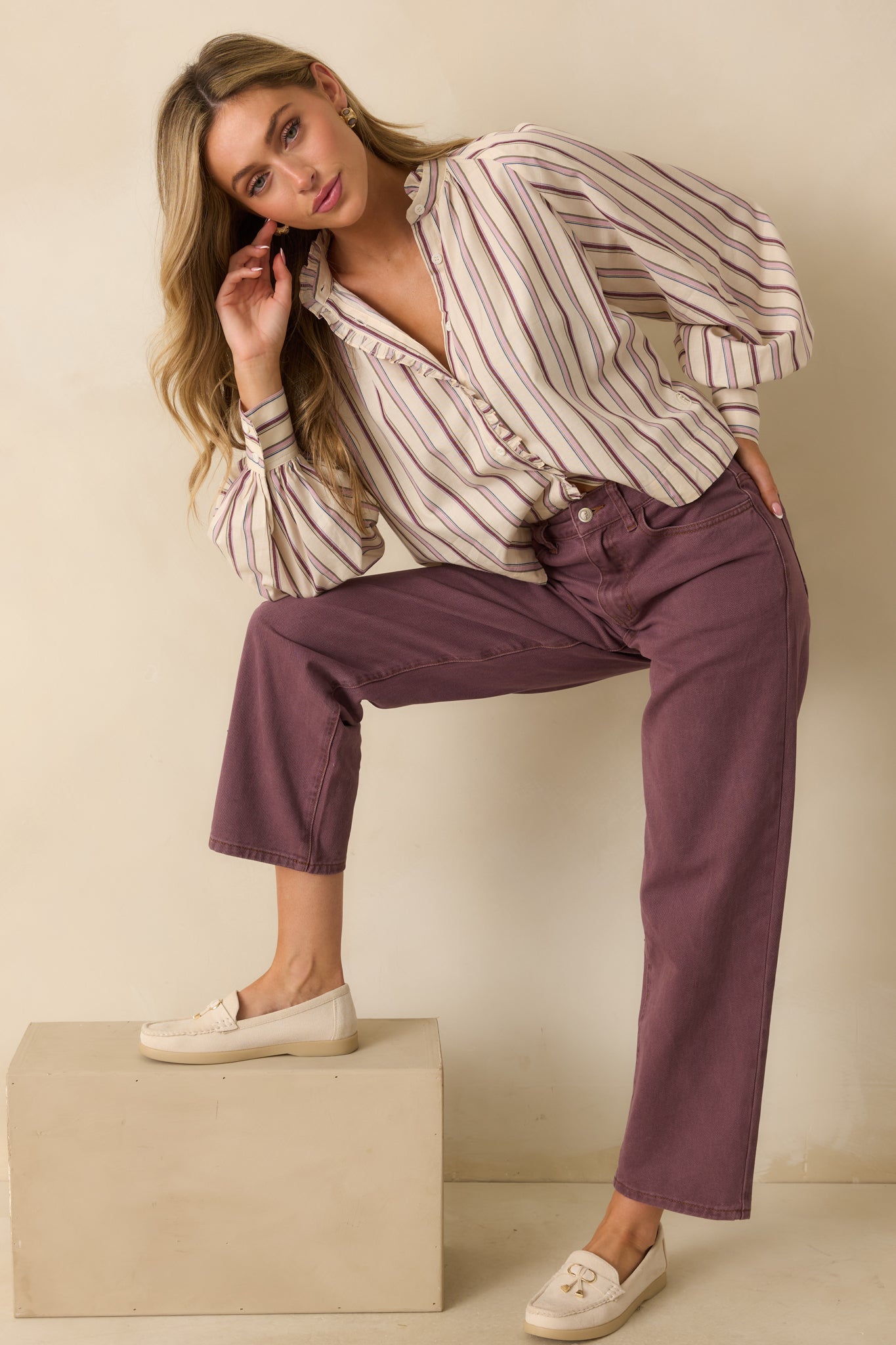 Ivory and lilac striped button-up shirt with a relaxed fit, showing its curved hemline and long balloon sleeves.