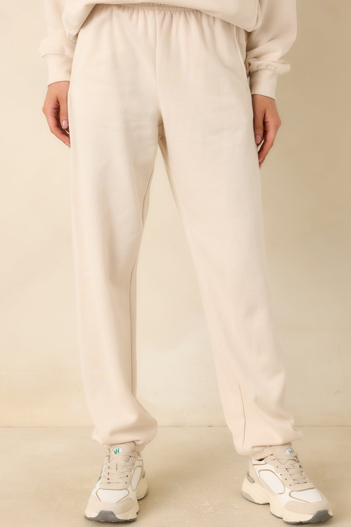Warm ivory-beige joggers featuring functional side pockets and a relaxed fit through the legs.
