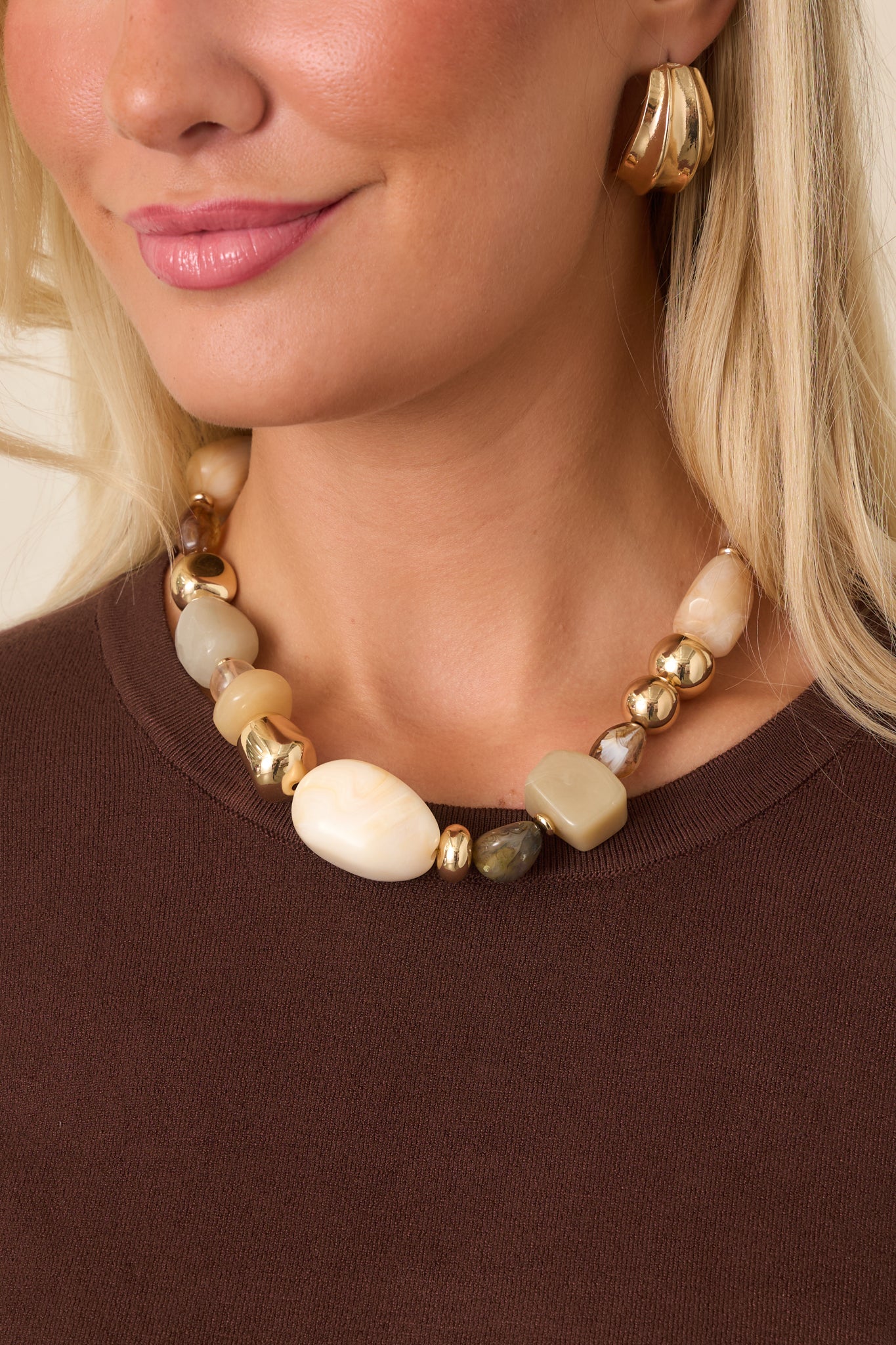 Statement necklace featuring smooth and marbled beads in ivory, beige, taupe, and brown, accented with polished gold-tone details.