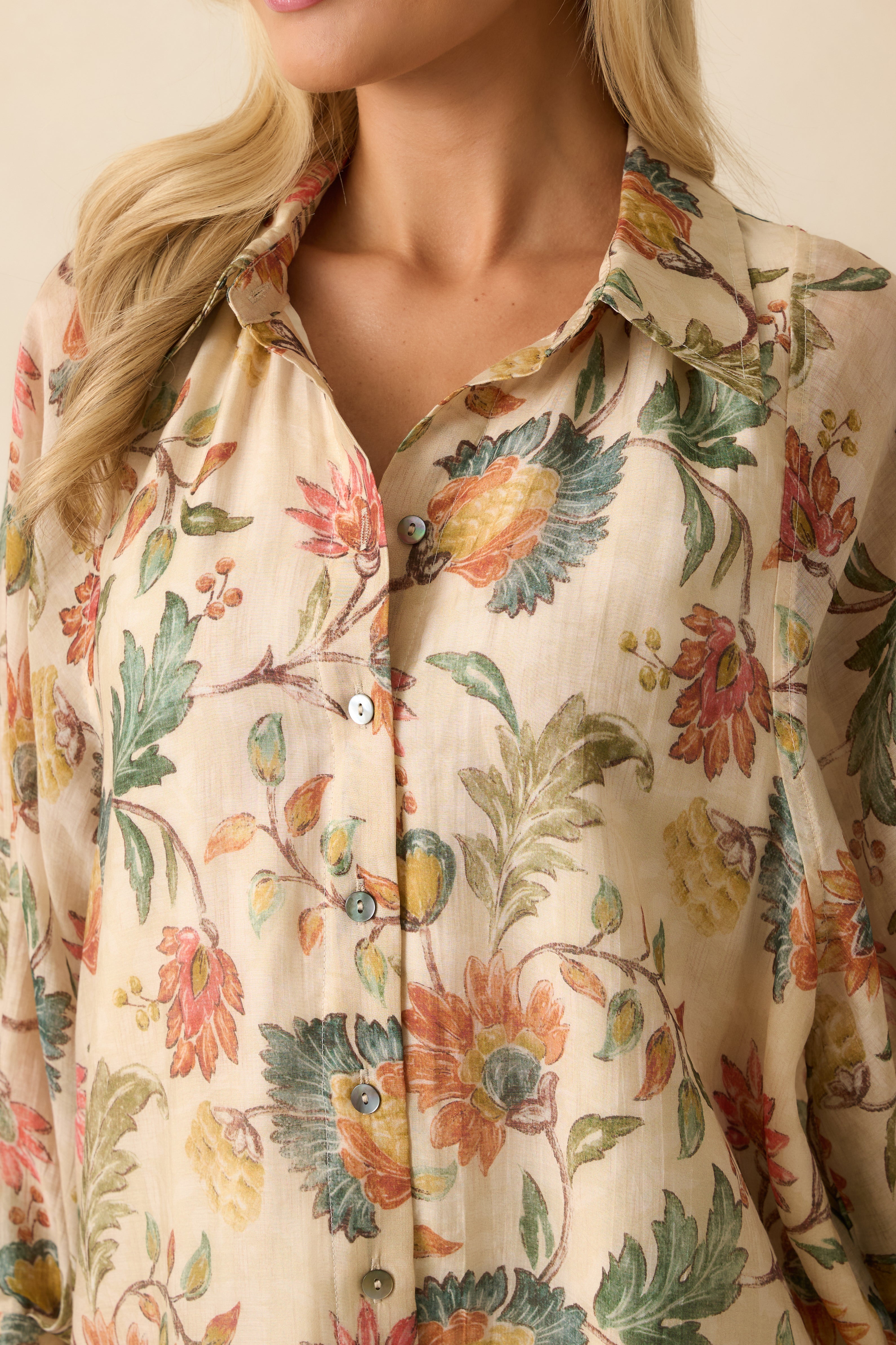 Close-up of the collared neckline, button closure, and delicate floral print on the ivory blouse.