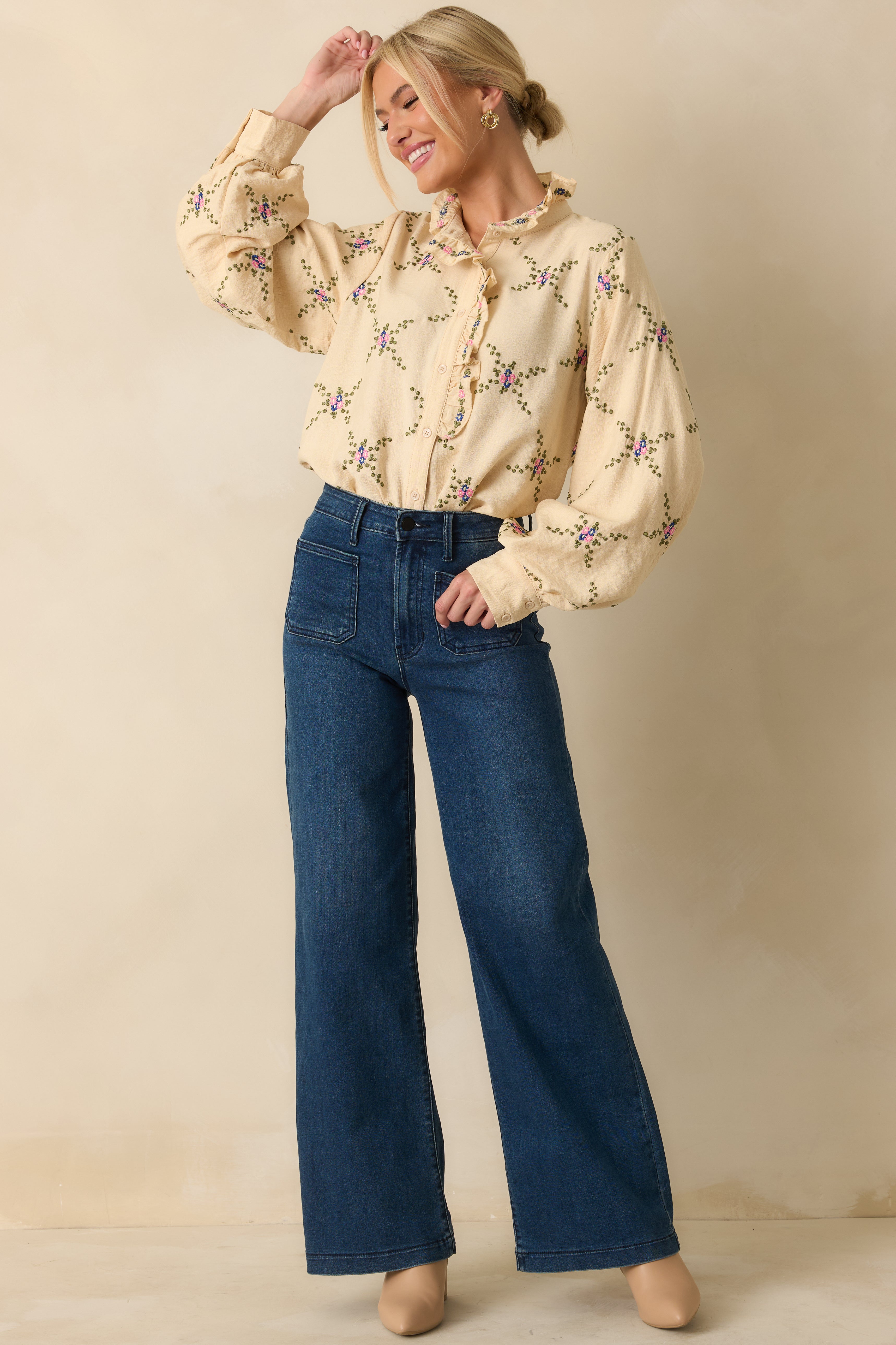Ivory blouse with multicolor floral embroidery, ruffled mock neckline, and long balloon sleeves.