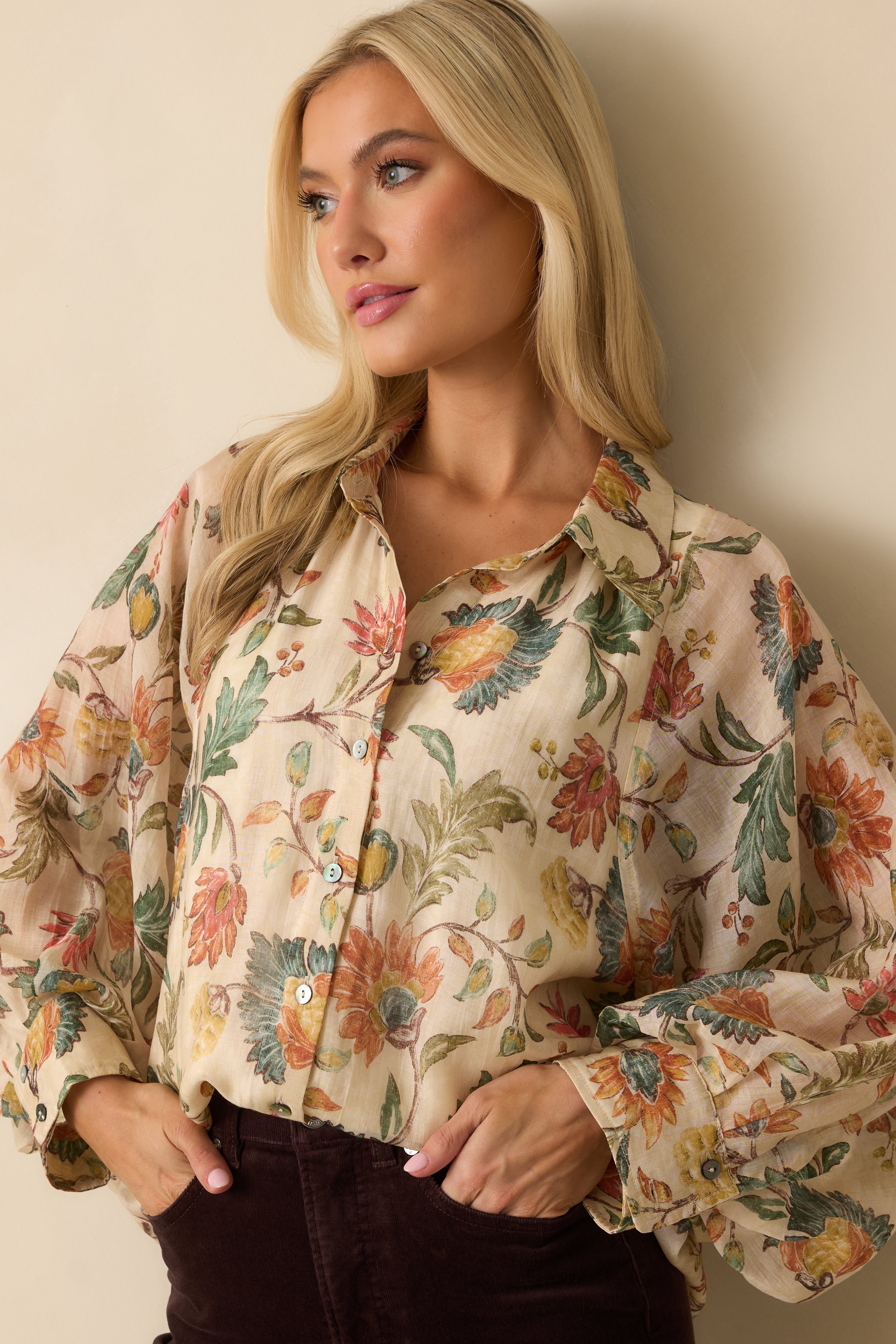 Detailed look at the floral print and flowing sleeve cuffs on the ivory blouse.