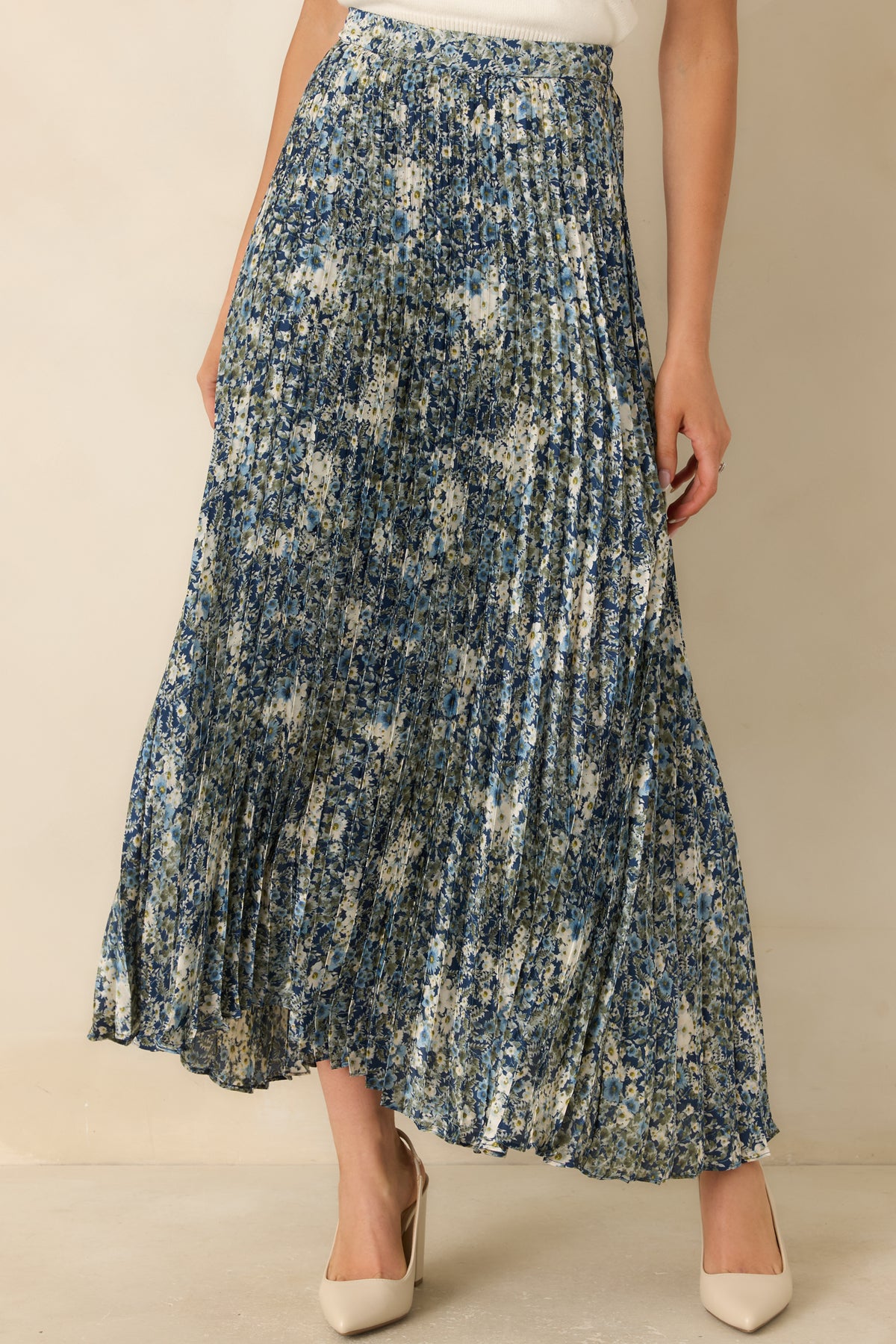 Ivory and soft blue blossoms with muted olive leaves decorate the pleated maxi skirt.