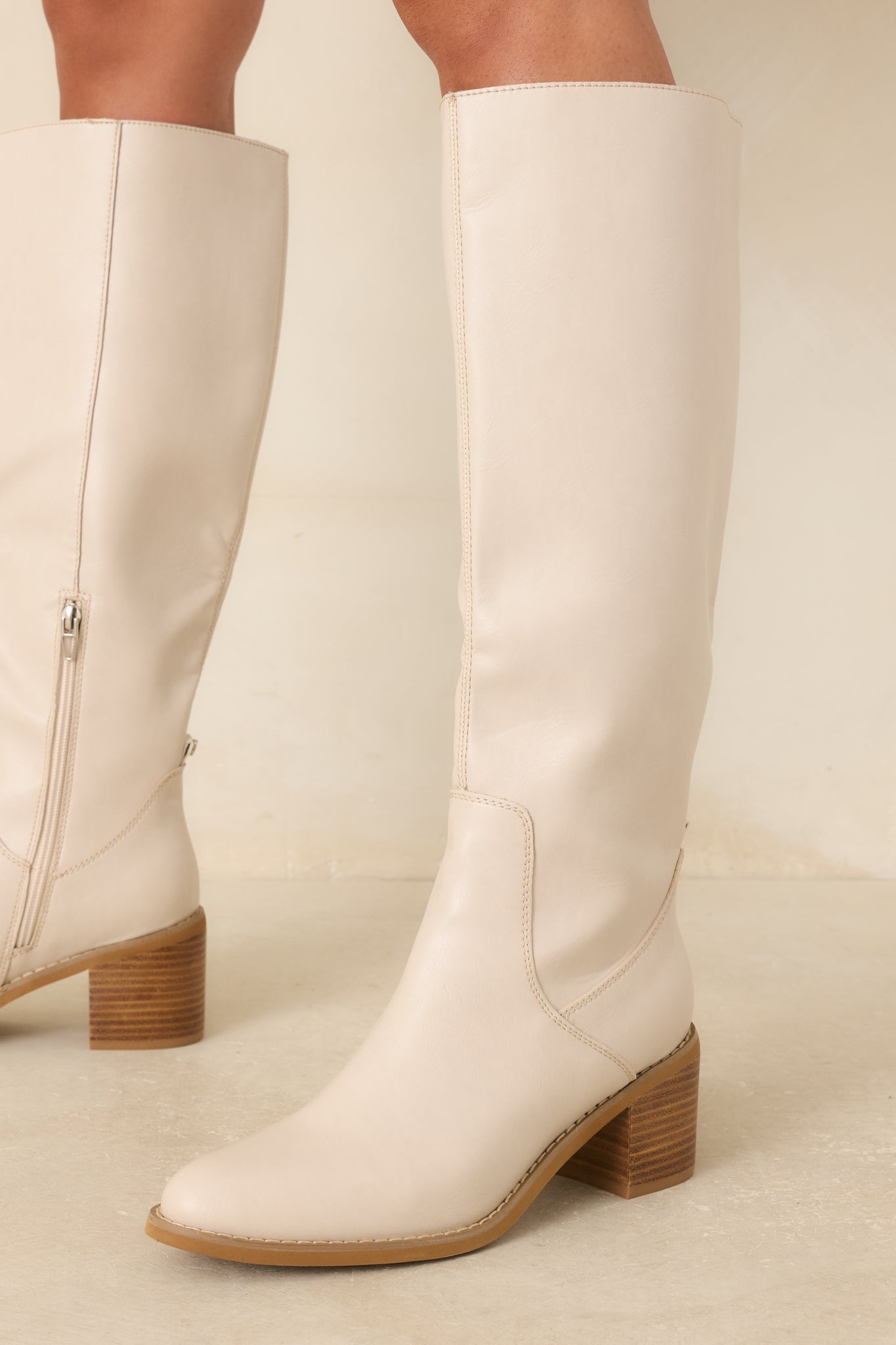 Close view of ivory boots showcasing the softly rounded almond toe, smooth faux leather texture, and refined front design.