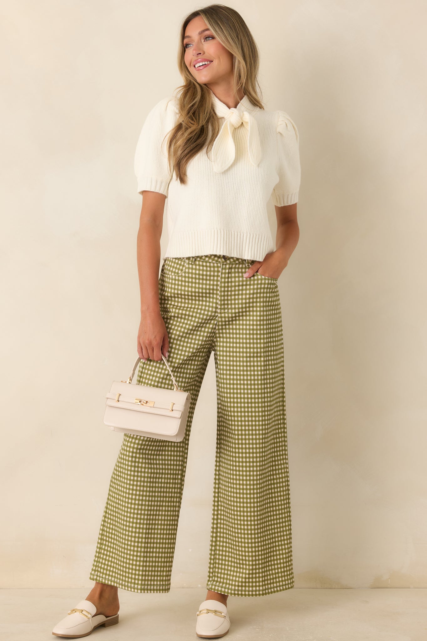 Elegant ivory knit top showcasing a fitted shape, oversized bow neckline, ribbed texture, and voluminous sleeves.