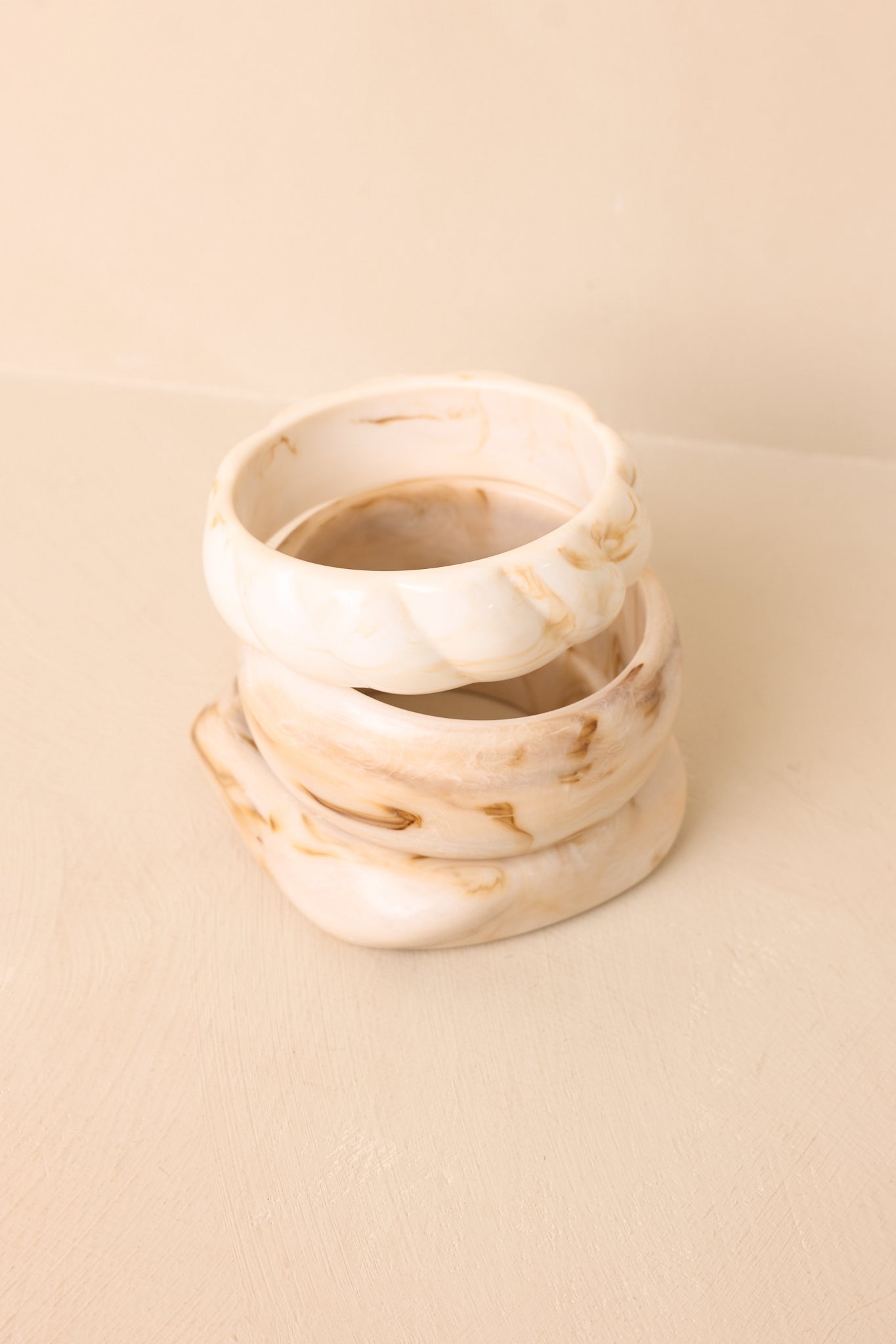 Coordinating ivory bracelet set featuring organic silhouettes and subtle marbled detailing on a beige backdrop.