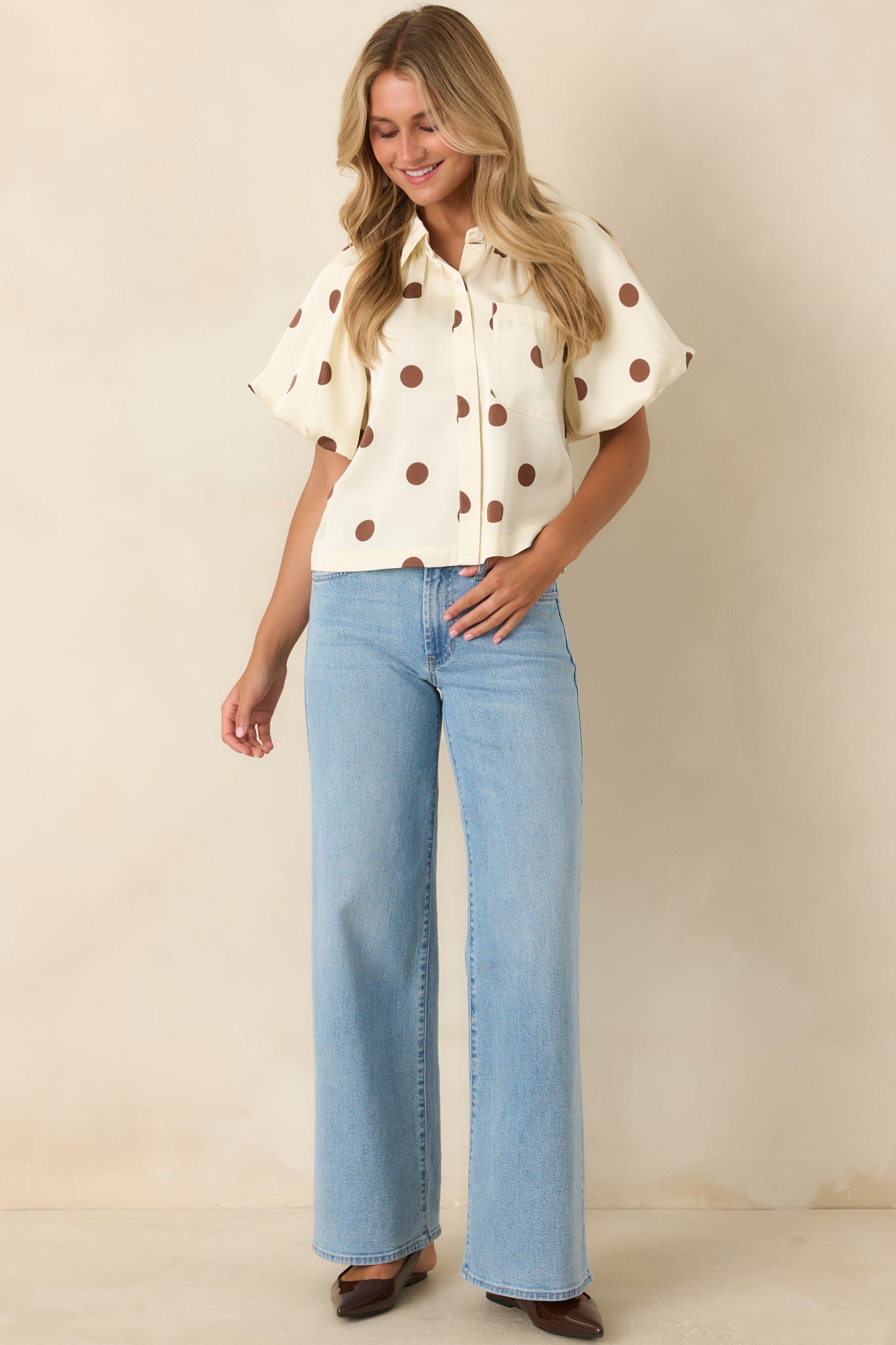 Ivory woven blouse featuring brown polka dots, puff sleeves, structured collar, concealed buttons, and chest pocket.