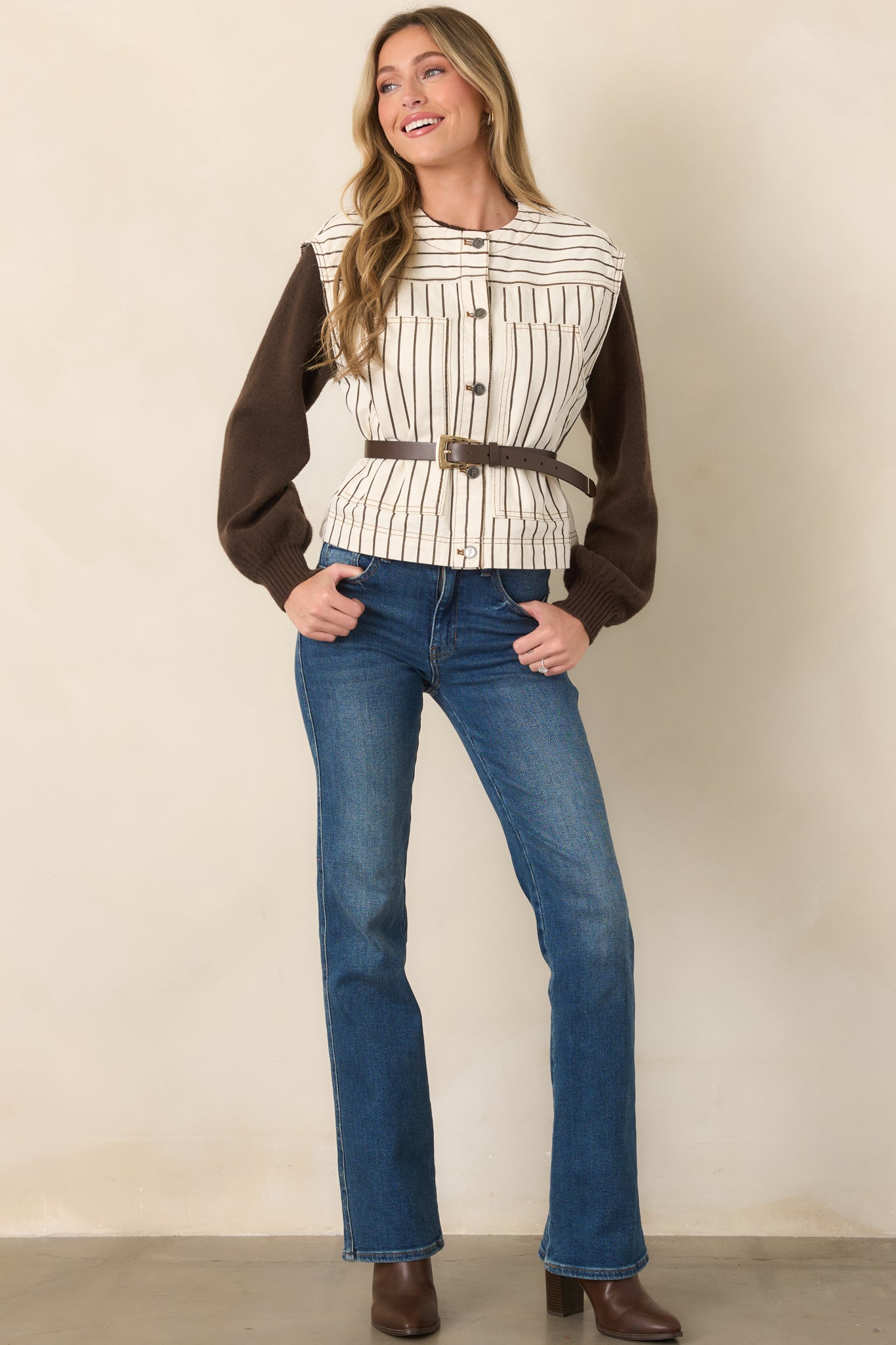 Relaxed ivory vest featuring vertical brown pinstripes, horizontal yoke striping, cap-style shoulders, and a utilitarian button-front finish.