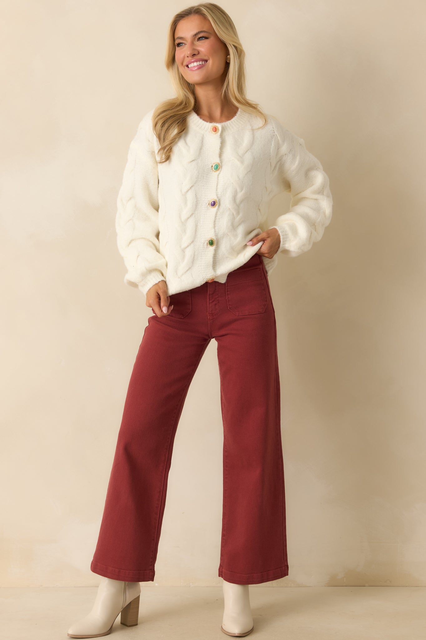 Relaxed-fit ivory cable knit cardigan highlighting ribbed edges, long sleeves, and colorful button accents.
