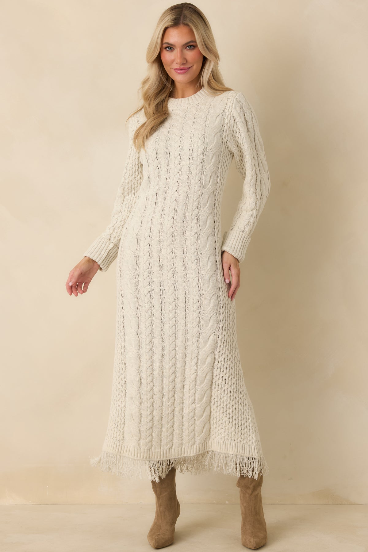 Ivory cable knit maxi dress with wide ribbed cuffs, textured knit panels, and a softly fringed bottom hem.