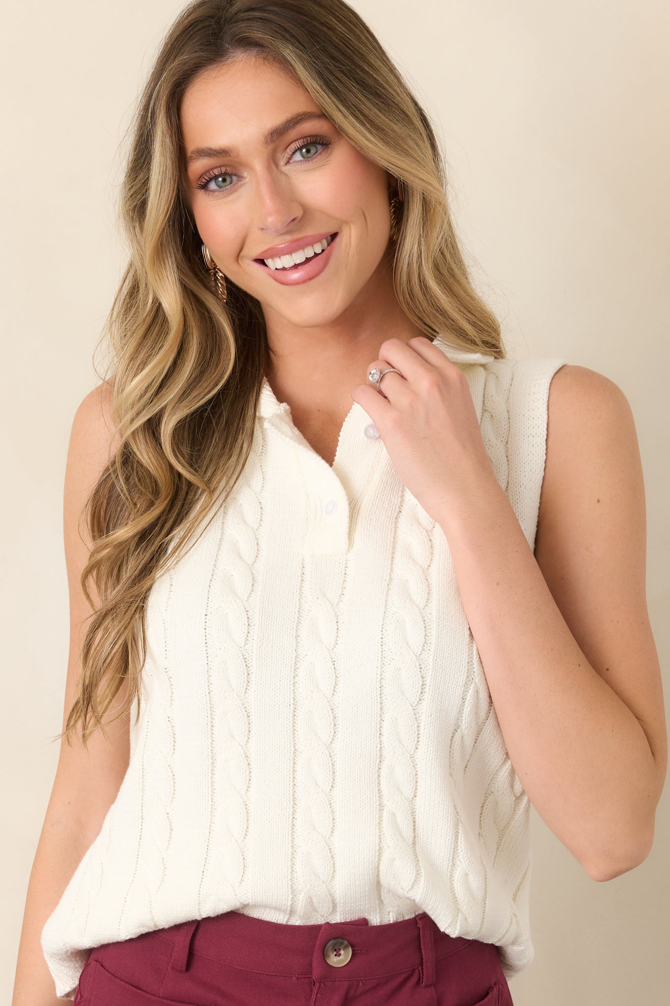 Close view of the ivory cable-knit texture and collared polo neckline, highlighting the dimensional knit pattern and button placket.