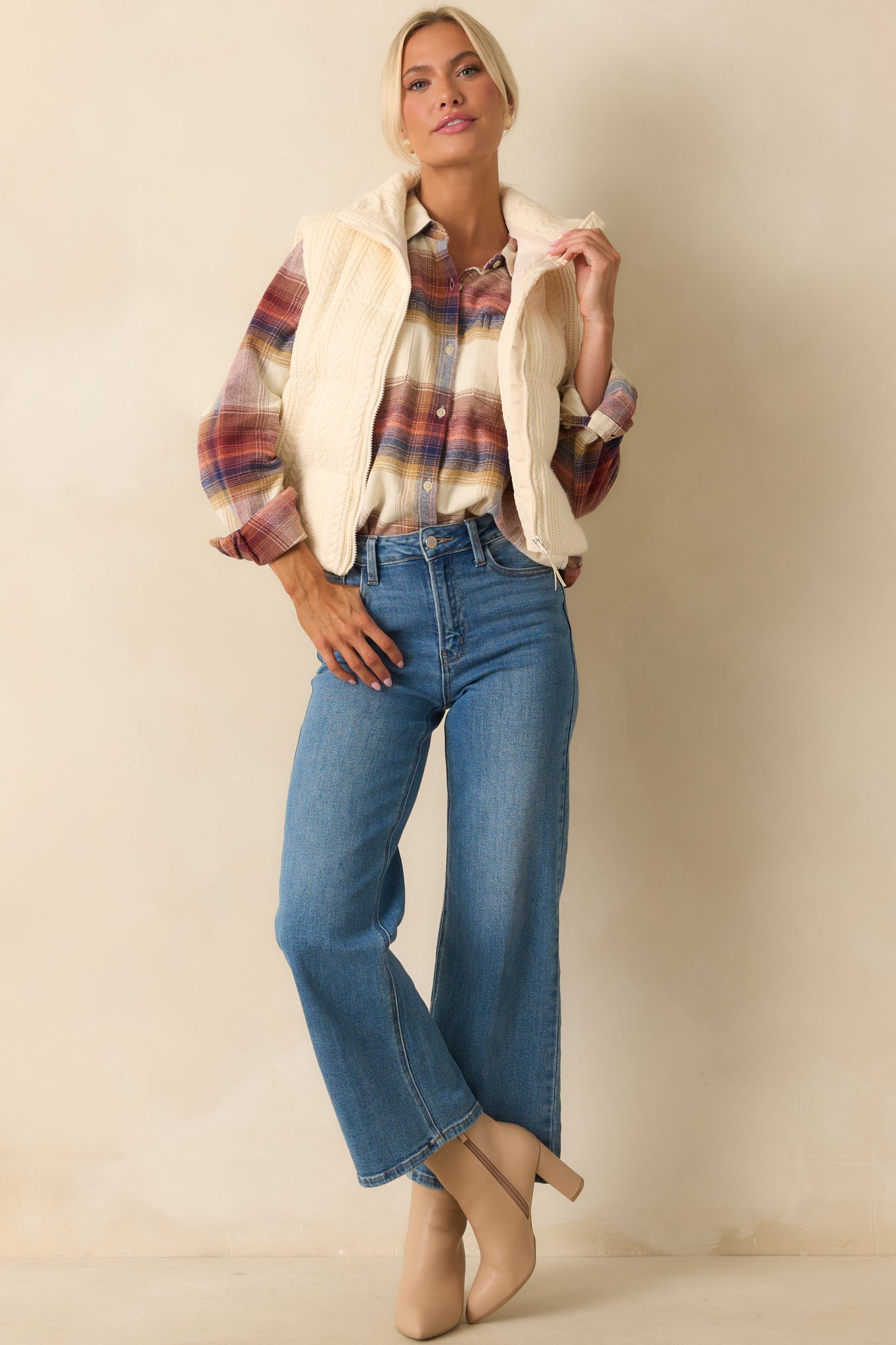 Ivory cable knit puffer vest with sleeveless cut, high stand collar, and zip-front closure with functional pockets.