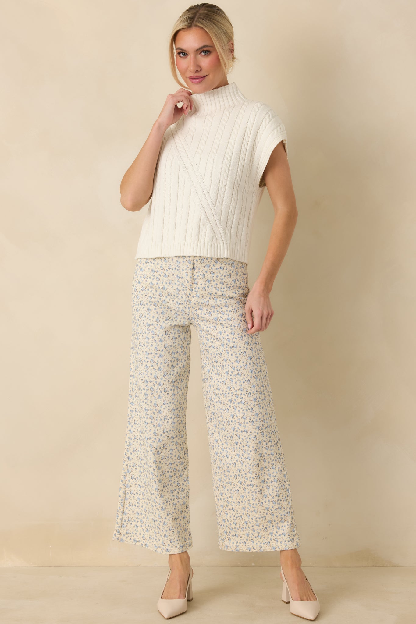 Ivory cable knit sleeveless mock neck sweater featuring a structured knit pattern and ribbed trim at the neckline and hem.