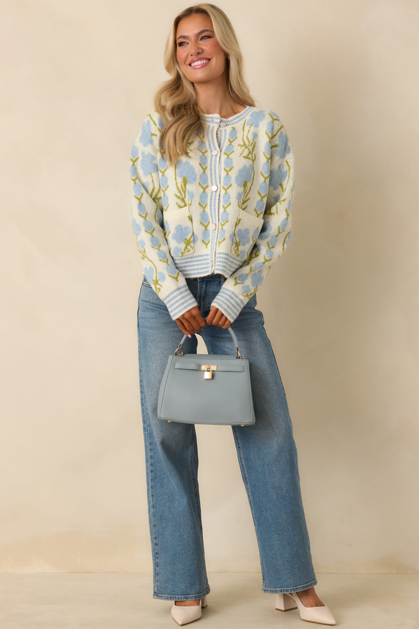 Floral ivory cardigan showing long sleeves, ribbed trim, and contrast striping along the hem and cuffs.