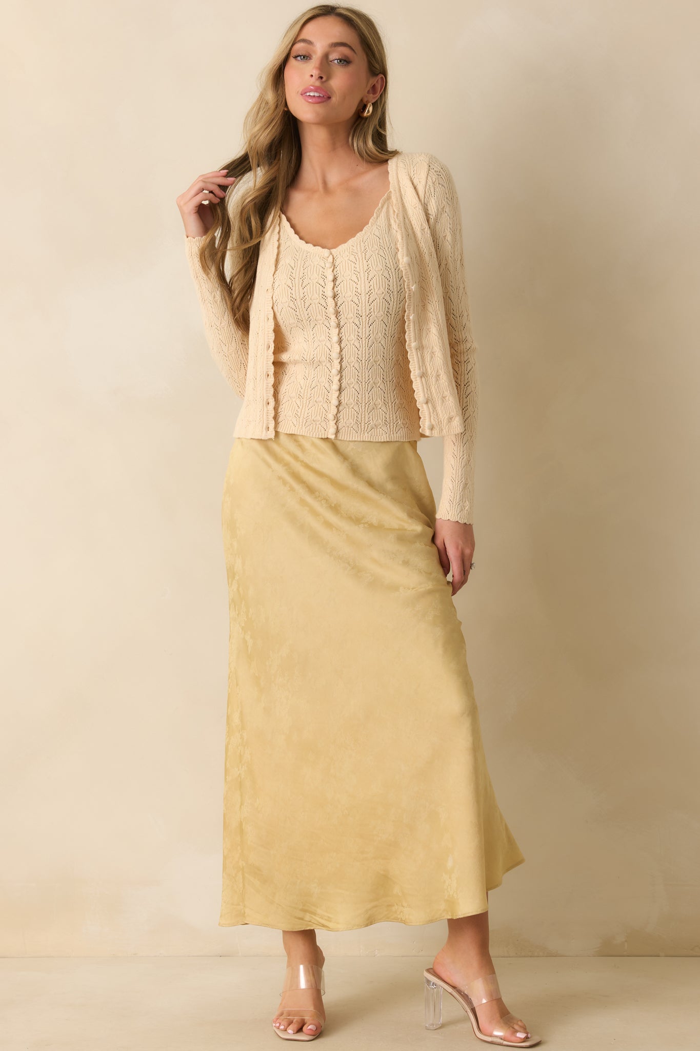 Ivory cardigan with scallop v-neckline, long sleeves, and cropped length, featuring a functional button front.