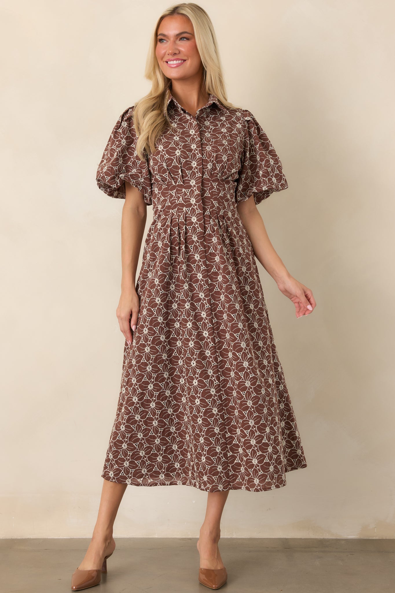 Full-length ivory cotton dress featuring allover floral eyelet embroidery, a crisp collar, short puff sleeves, fitted waist, and flowing midi skirt.