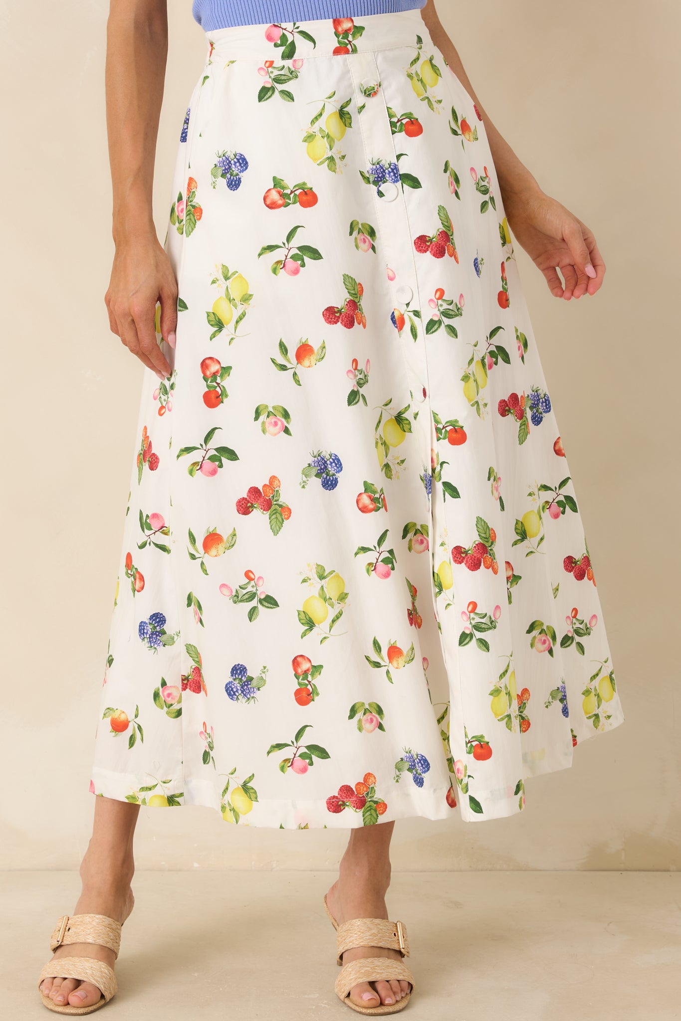 Close-up of ivory cotton fabric skirt showcasing colorful fruit motifs, faux buttons, and soft texture