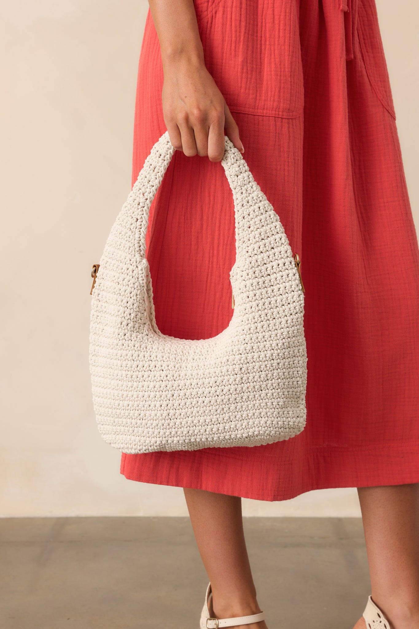 The ivory crotchet handbag featuring an optional gold chain strap, canvas lining, and gold hardware.