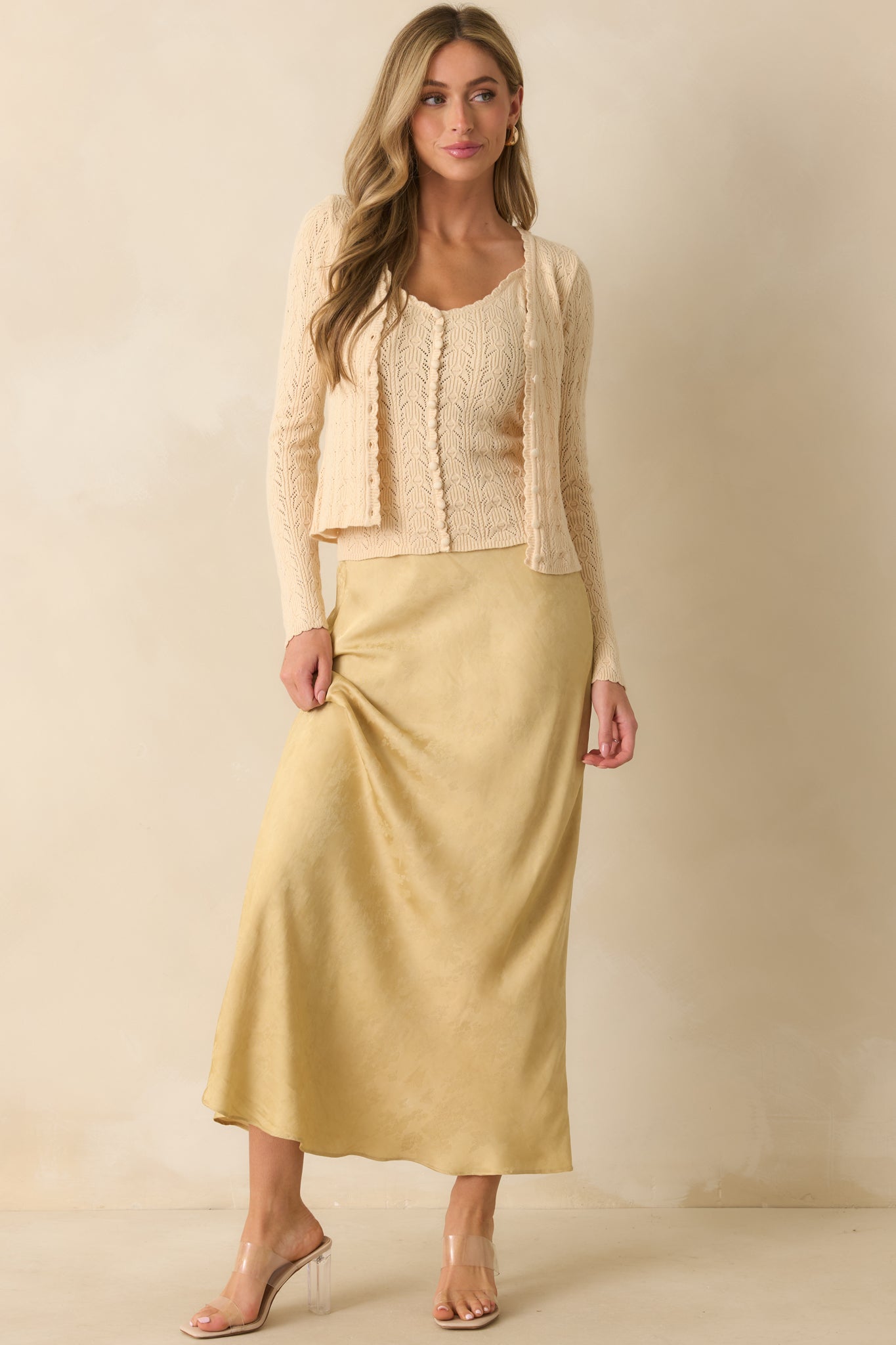 Ivory cropped cardigan showing long sleeves, button closure, and airy knit texture.