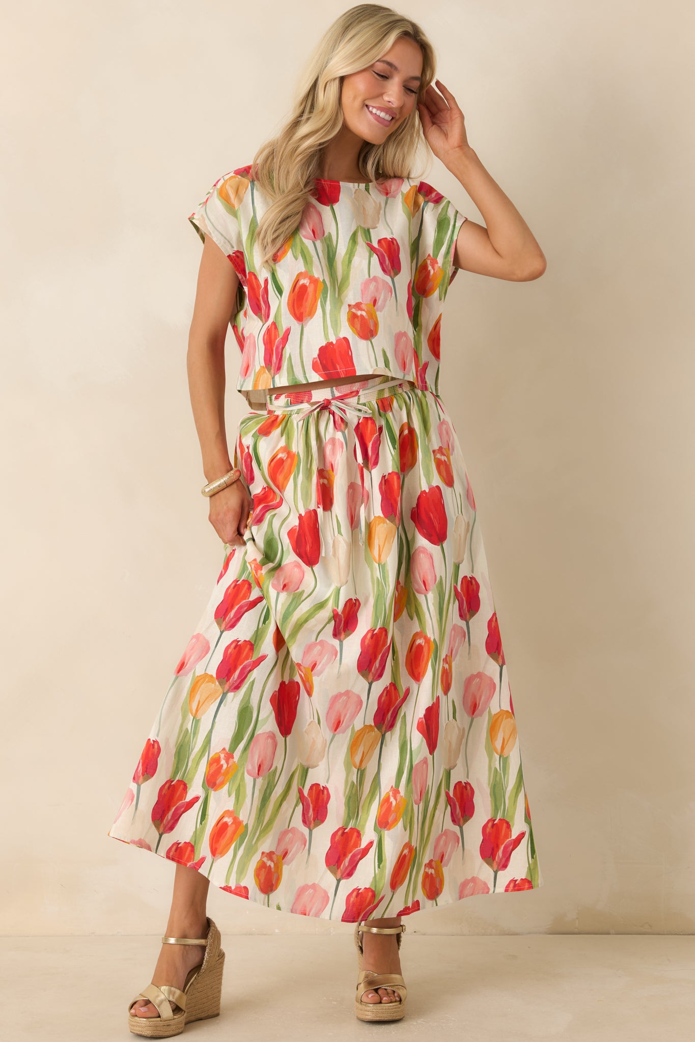 Ivory cropped top with a colorful tulip floral print, relaxed silhouette, cap-style sleeves, and lightweight linen blend fabric.