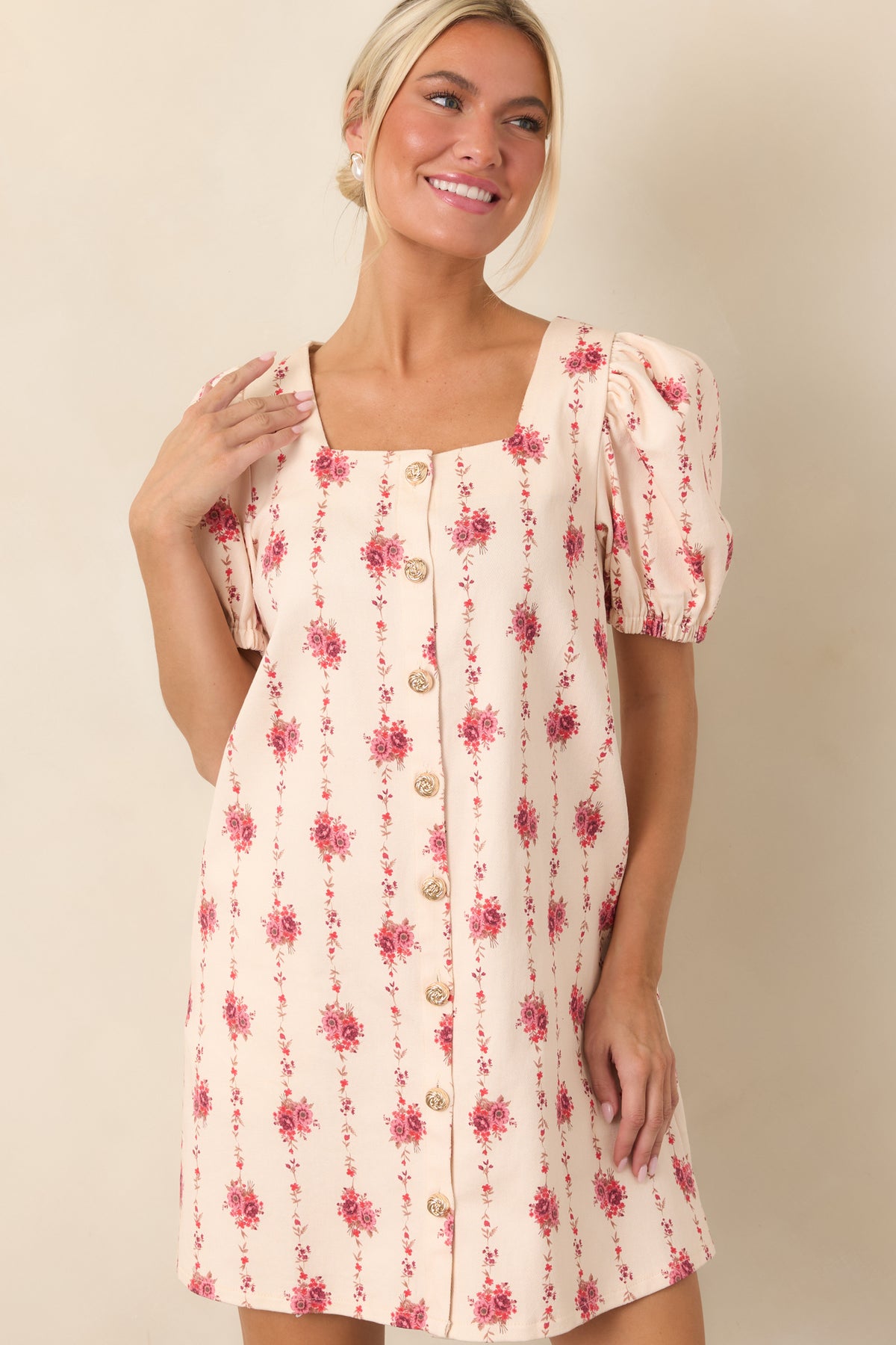 Detailed view showcases the delicate rose-and-vine pattern and softly puffed sleeves against the ivory backdrop.