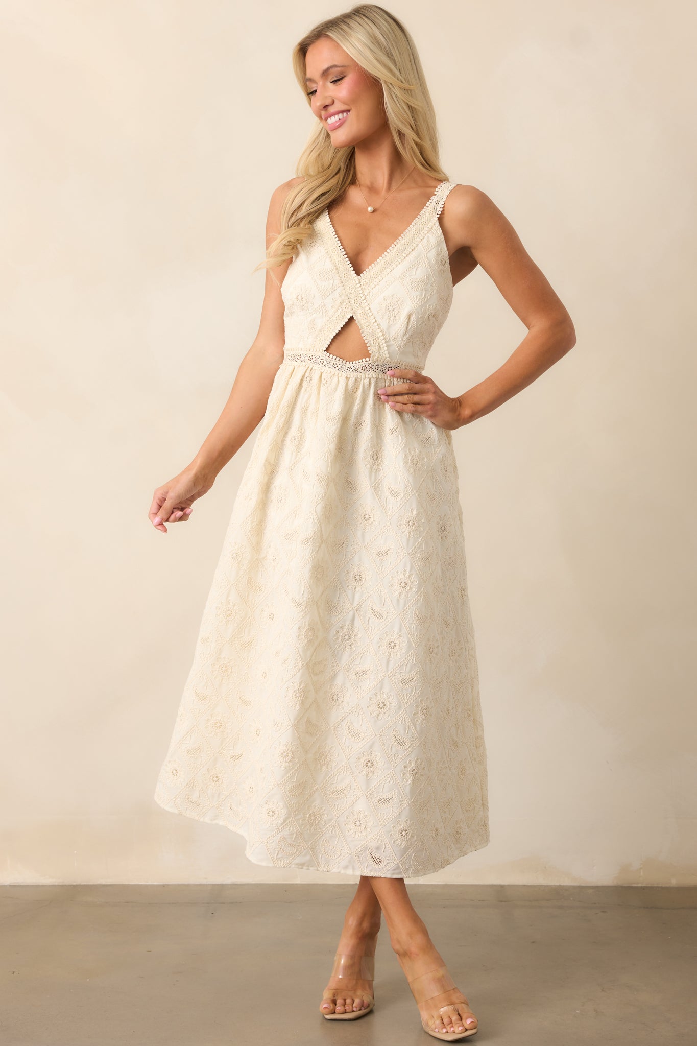 An elegant ivory dress with lace embroidery details, a v-neckline, and a cutout in the center of the bodice, complete with adjustable straps for an adjustable, perfect fit.