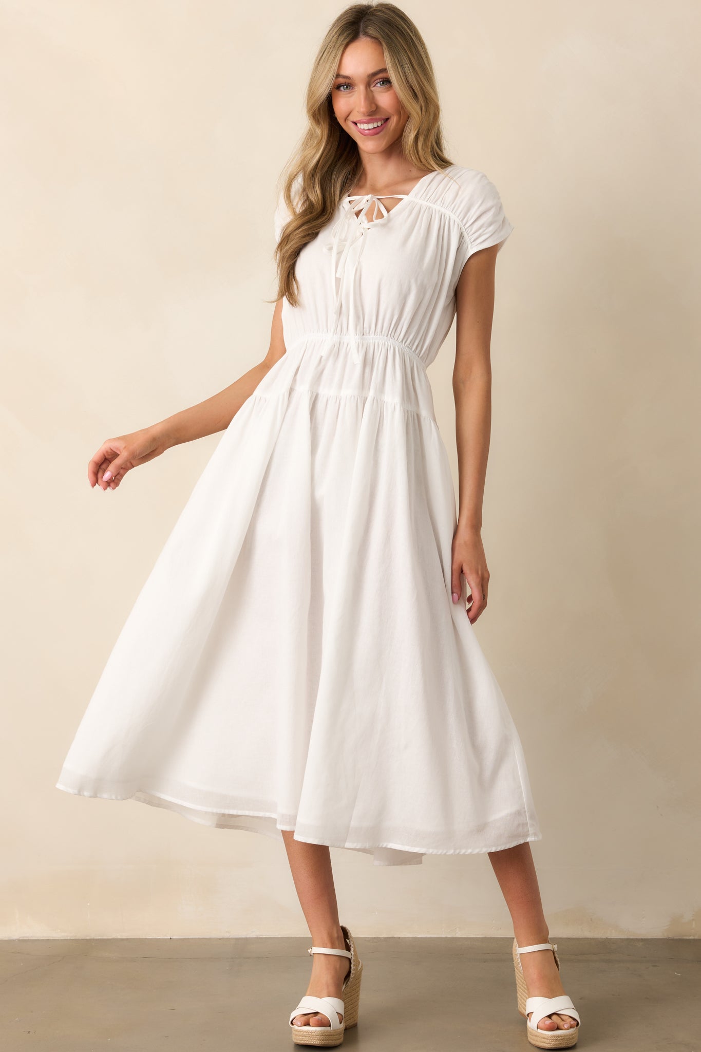 The ivory dress drapes beautifully with a v-neckline, self-tie bows, short cap sleeves, an elastic waist, and pockets for an effortlessly chic look.