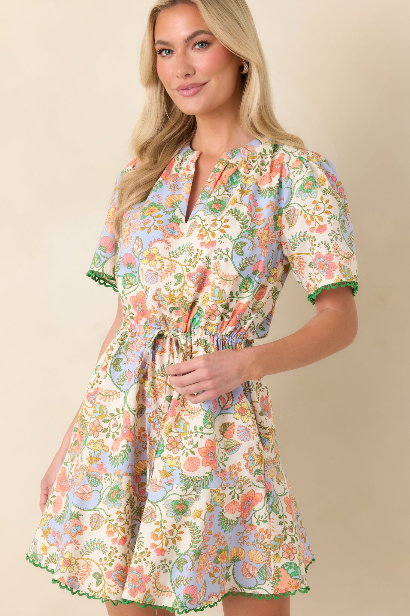 Detail of the ivory fabric with multi floral paisley print and subtle green scallop trim along the hem.