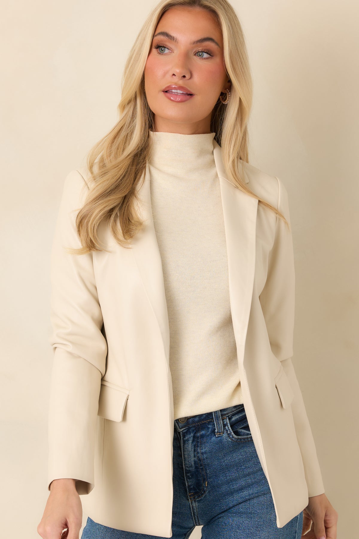 Functional flap pockets add a practical accent to the ivory faux leather blazer.