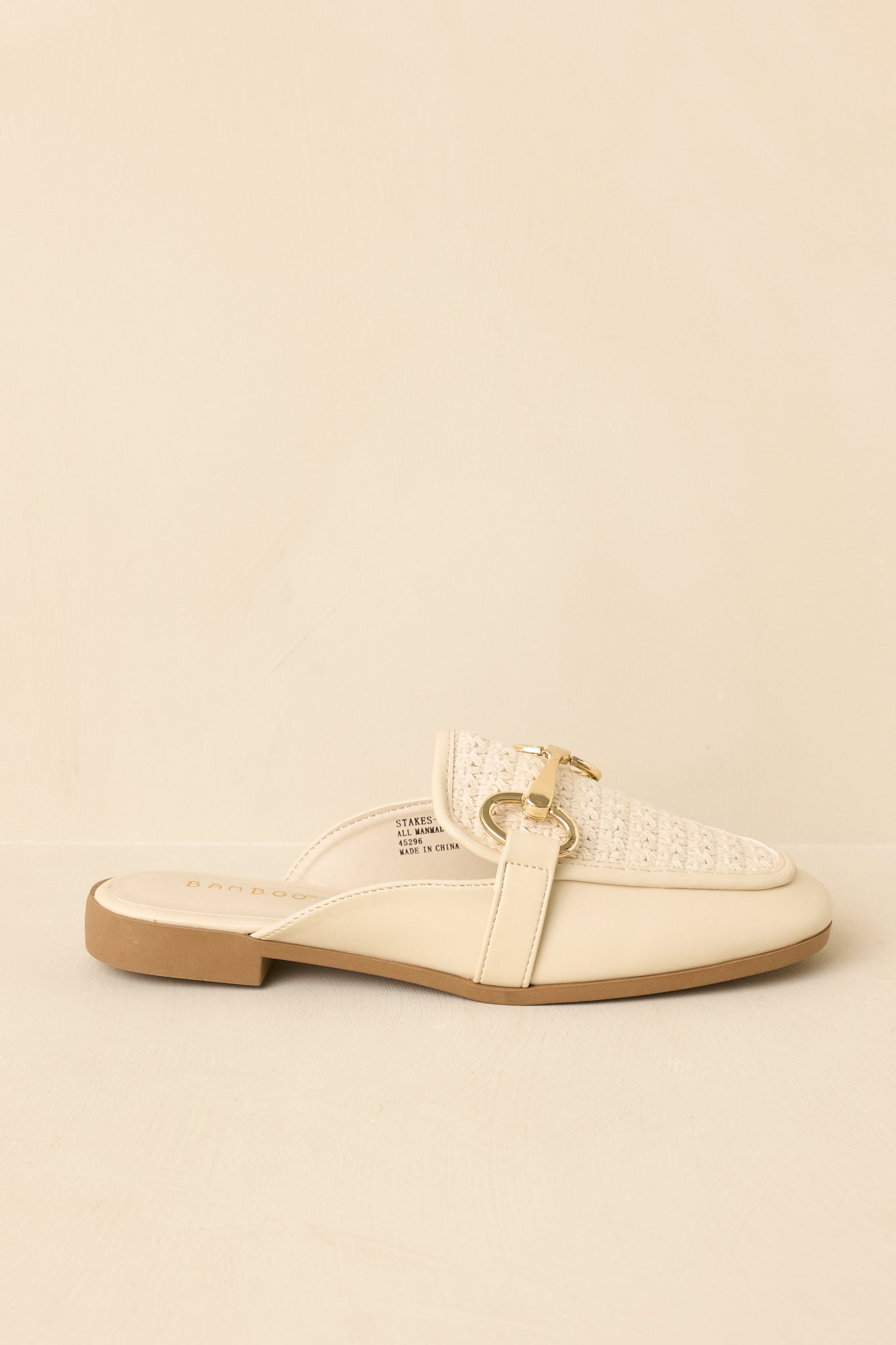 Cropped side view of ivory woven faux leather mule loafers featuring a slip-on open-back silhouette and gold-tone hardware detail.