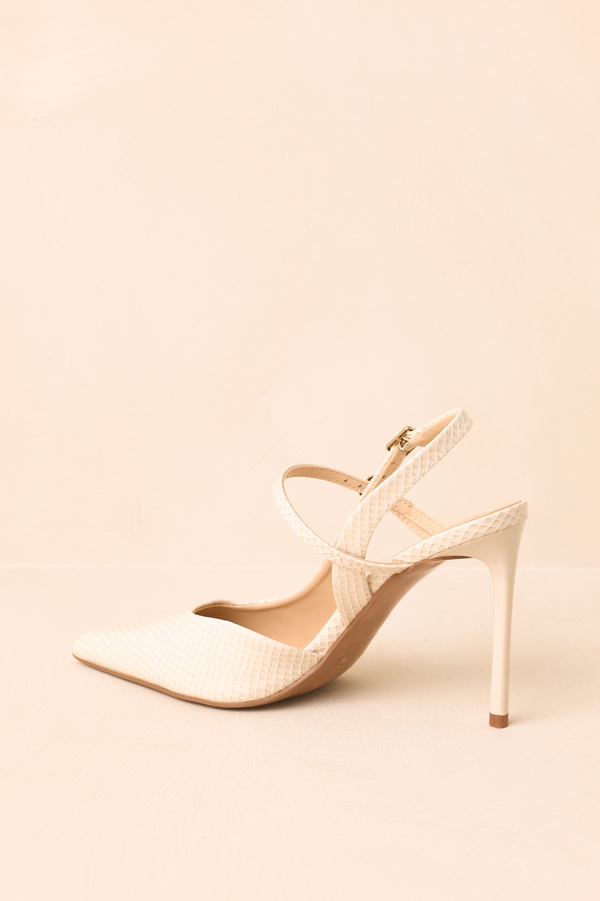 Ivory faux snakeskin heels present a streamlined pointed-toe shape with a slim stiletto heel and slingback construction.
