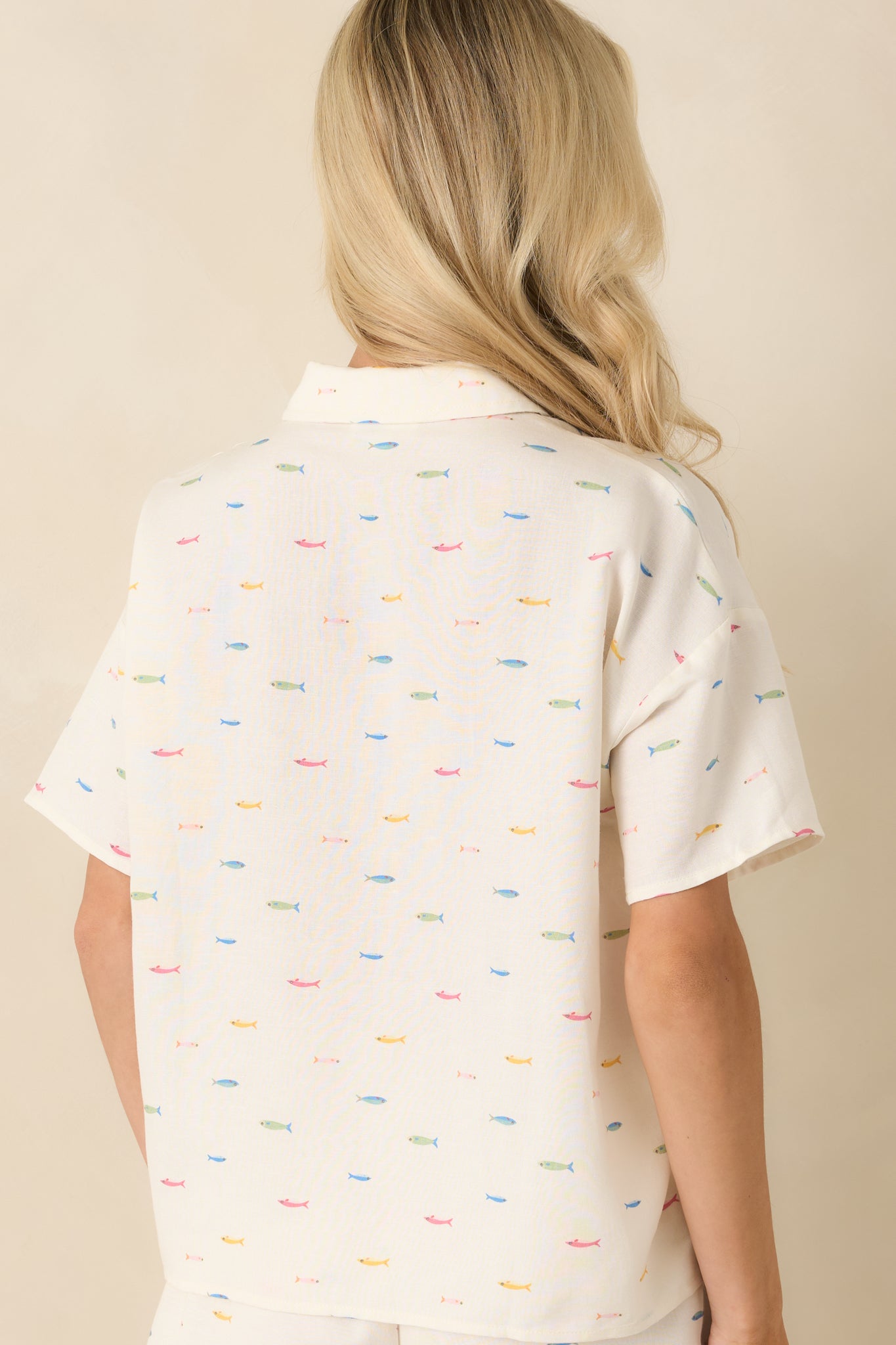 Rear view of the ivory button-up top featuring the allover multicolored fish print and relaxed silhouette.