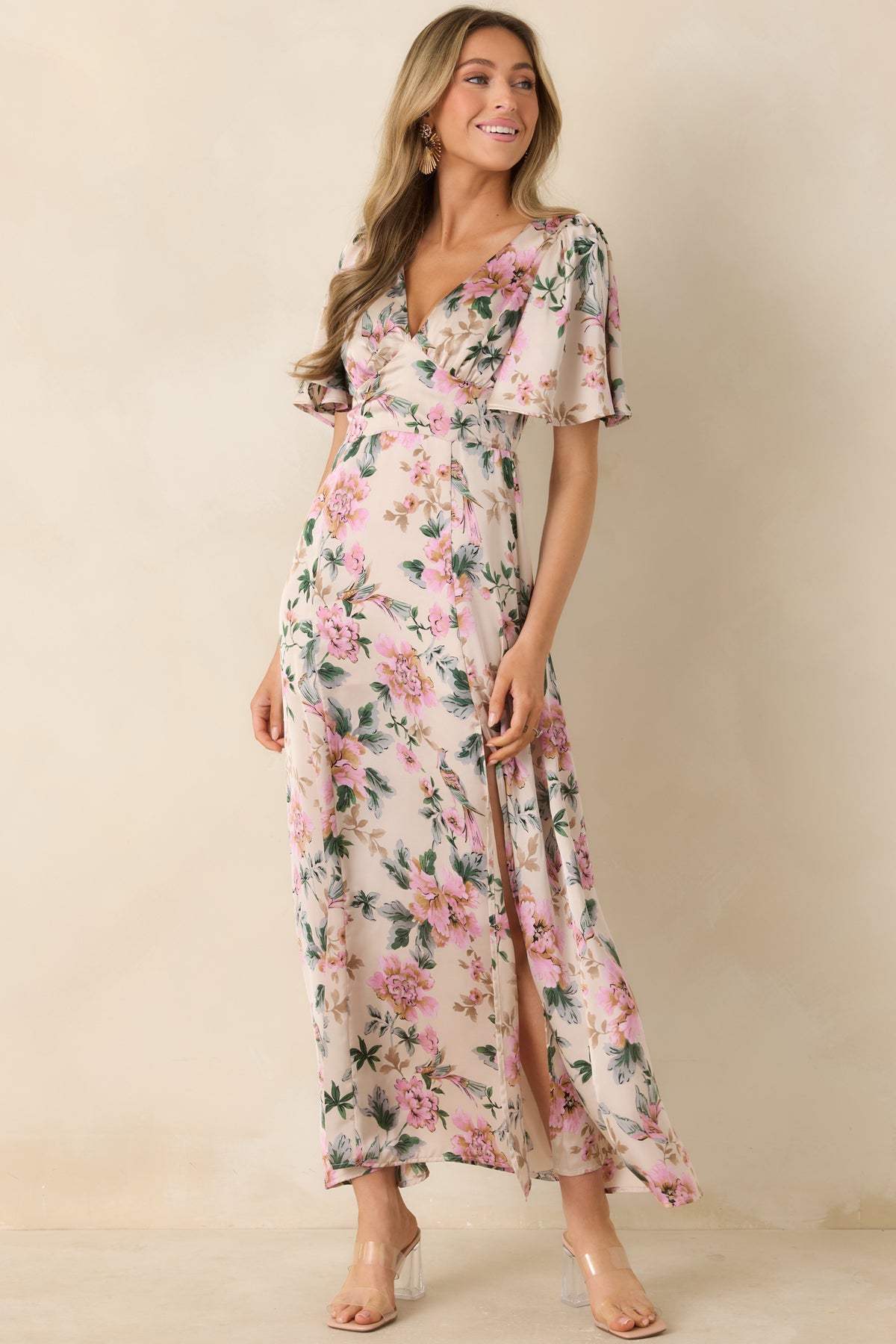 A full view of the ivory floral maxi dress, featuring a deep V-neckline and flutter sleeves, showcasing the vibrant floral print and fitted waist that creates an elegant silhouette.