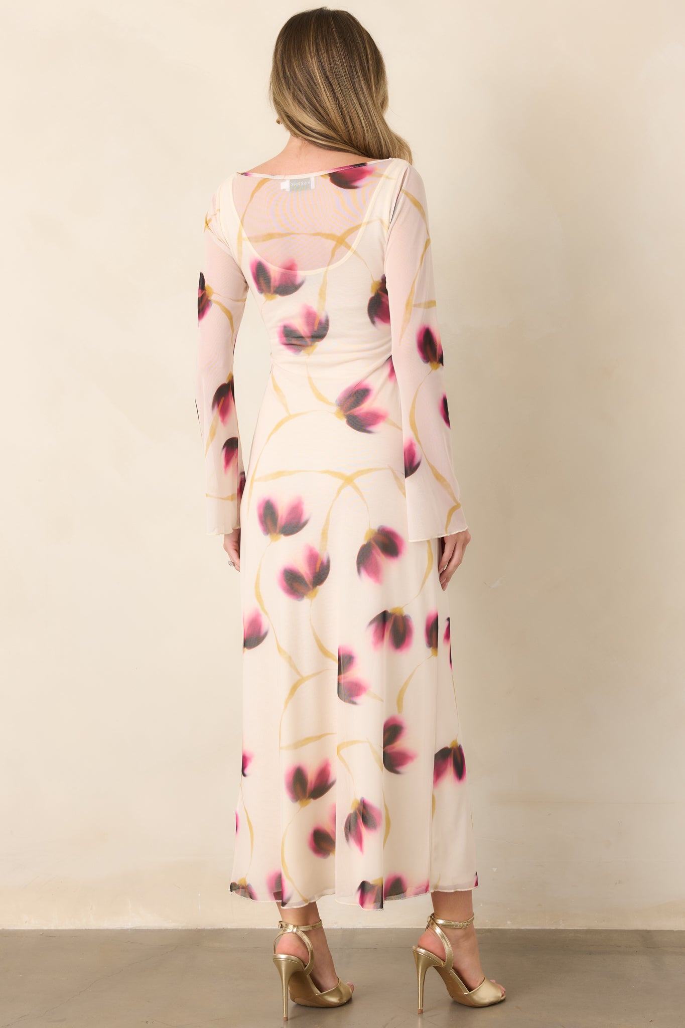 Rear view of the ivory floral mesh maxi dress, highlighting its close-fitting silhouette, full-length design, long sleeves, and subtle flared cuffs.