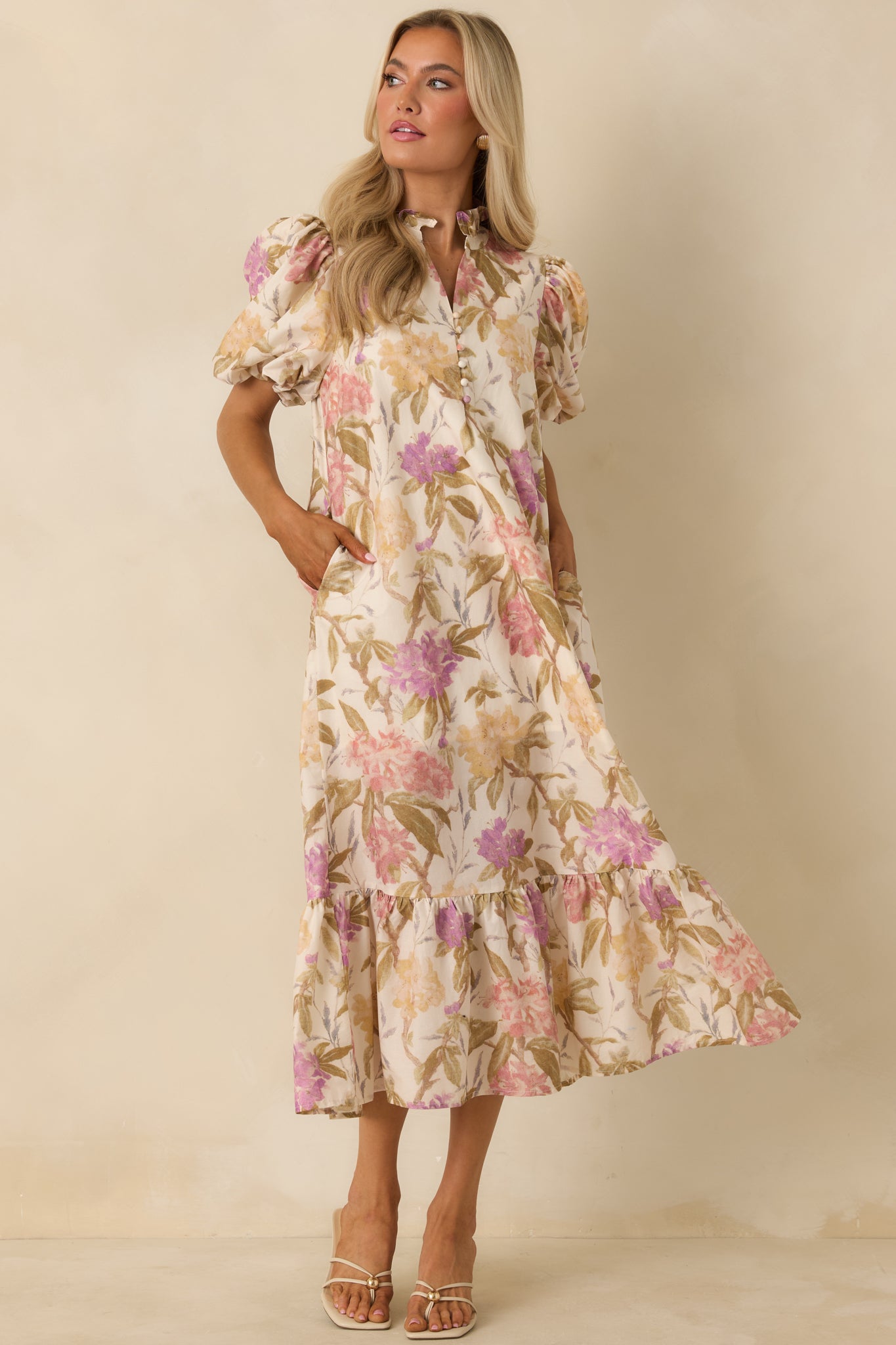 Ivory floral midi dress designed with short puff sleeves, a ruffled stand collar, and fabric-covered buttons along the front placket. The relaxed shape and gathered hem add light movement and comfort.