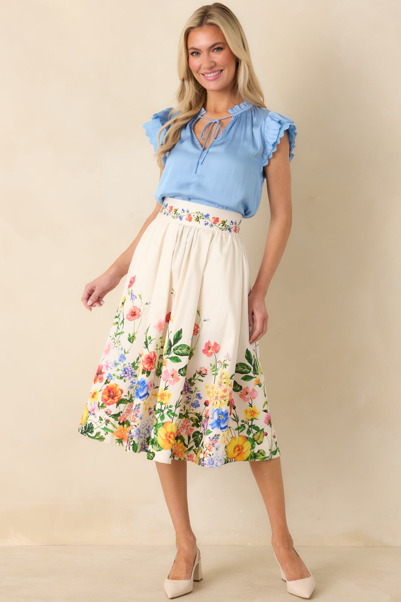 Ivory floral midi skirt shown in full length, highlighting the flowy fabric and floral border print concentrated at the hem.