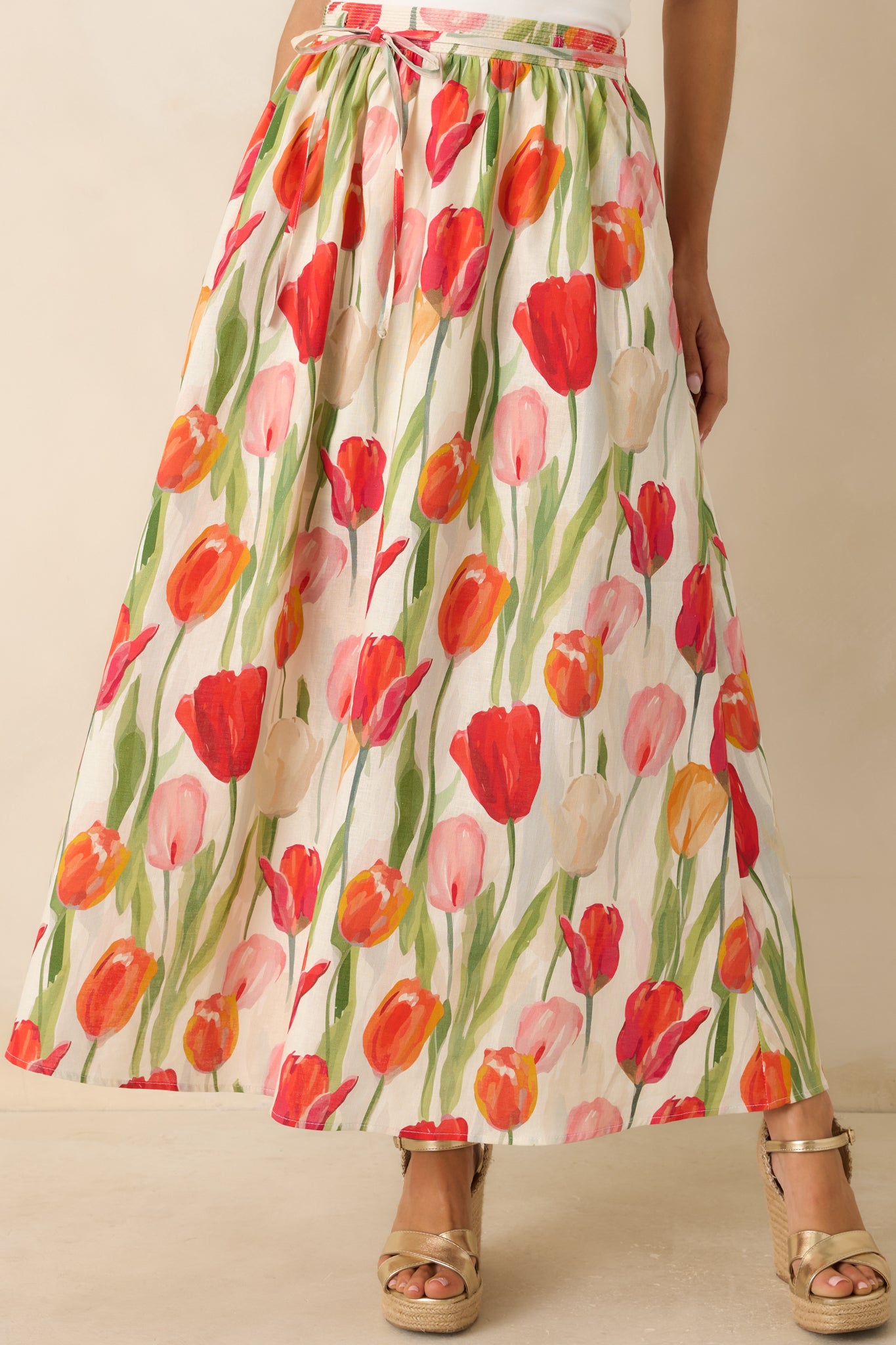 Close view of the ivory floral midi skirt showcasing the red multi-colored tulip print and smooth mini-length lining beneath.