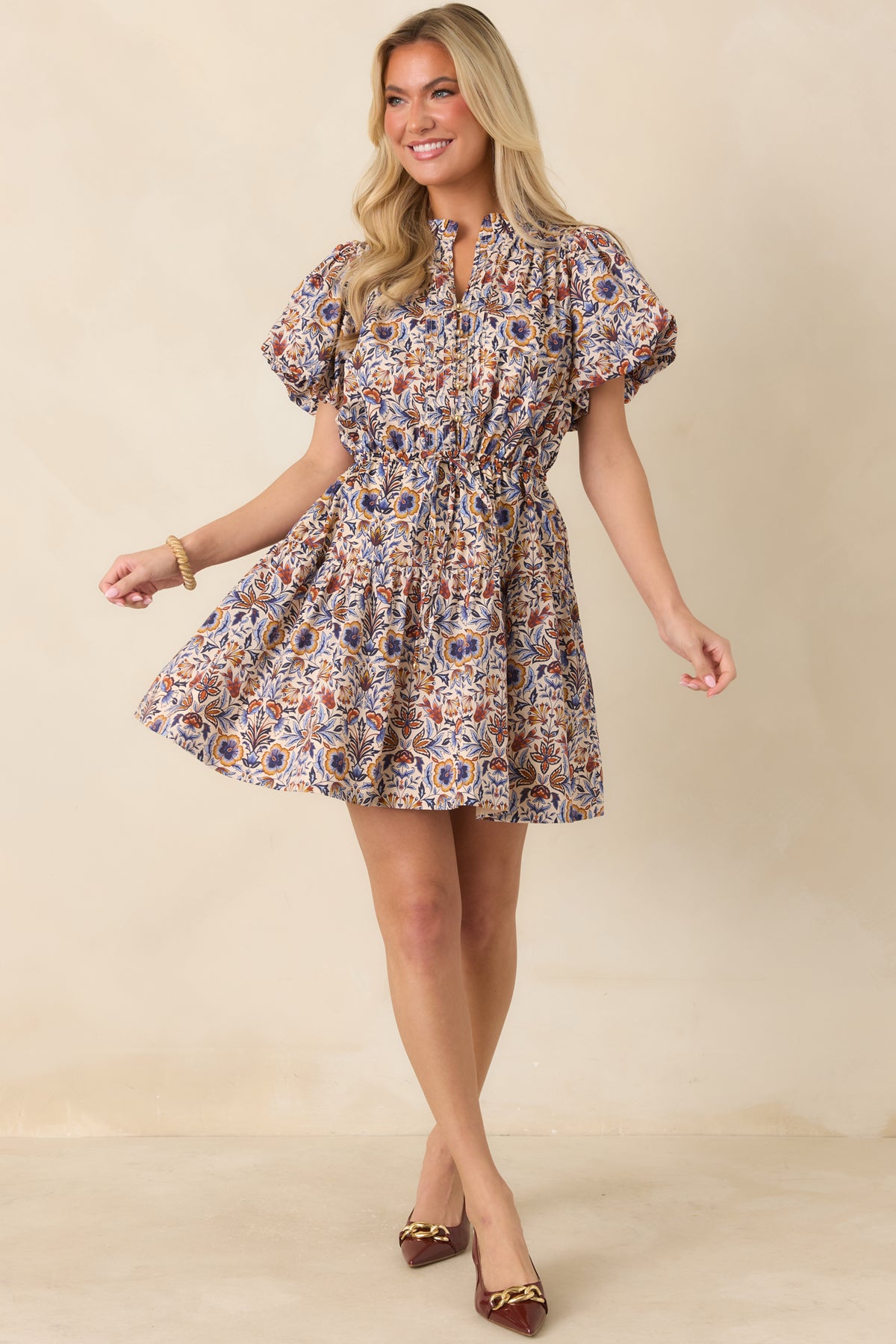 Ivory cotton mini dress showcases a split neckline, gold-tone buttons, and an adjustable drawstring waist.