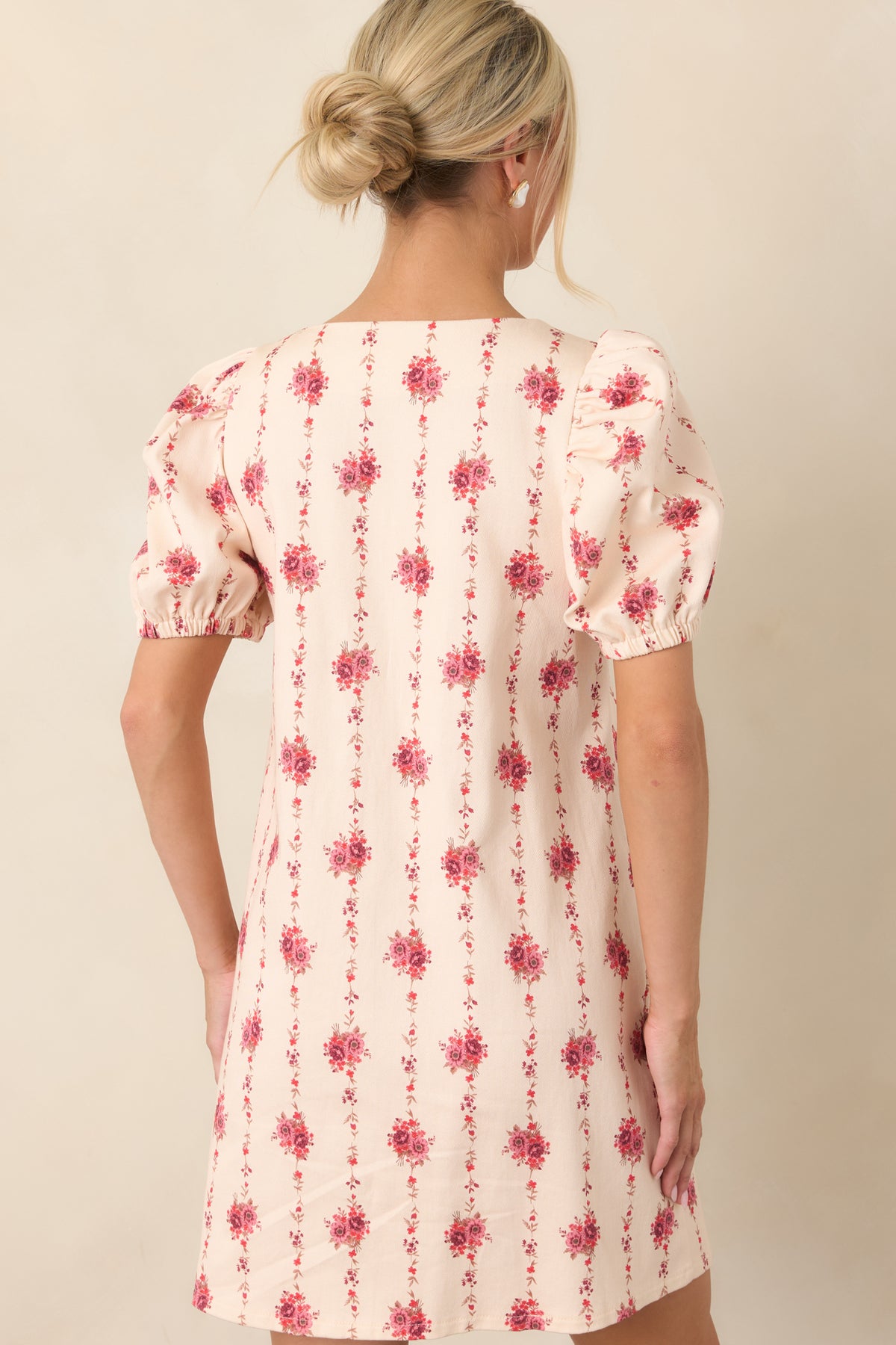 Rear view of the ivory floral mini dress showcasing the trailing vine pattern, puffed sleeves, and structured silhouette.