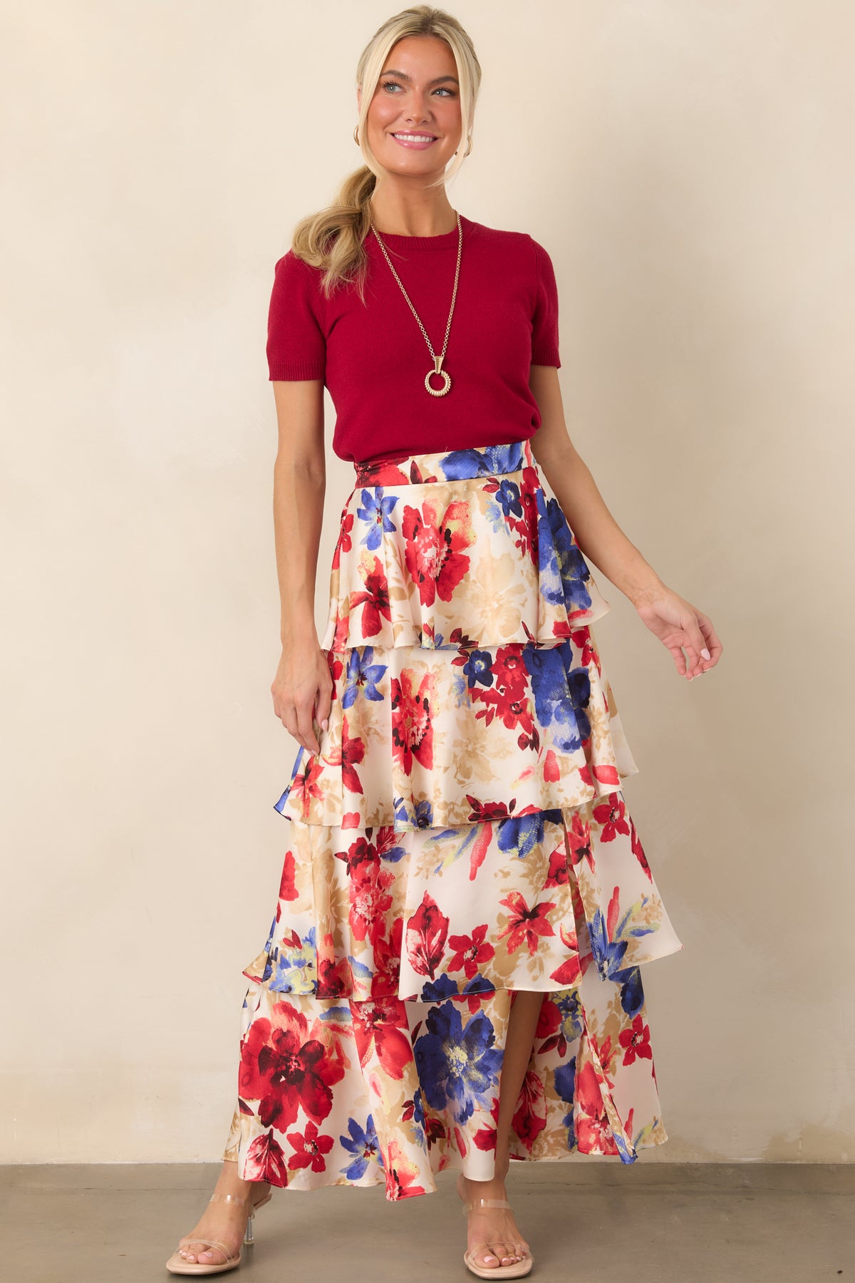 Feminine floral maxi skirt with layered tiers, an airy full-length silhouette, and a vibrant ivory and red allover botanical print.