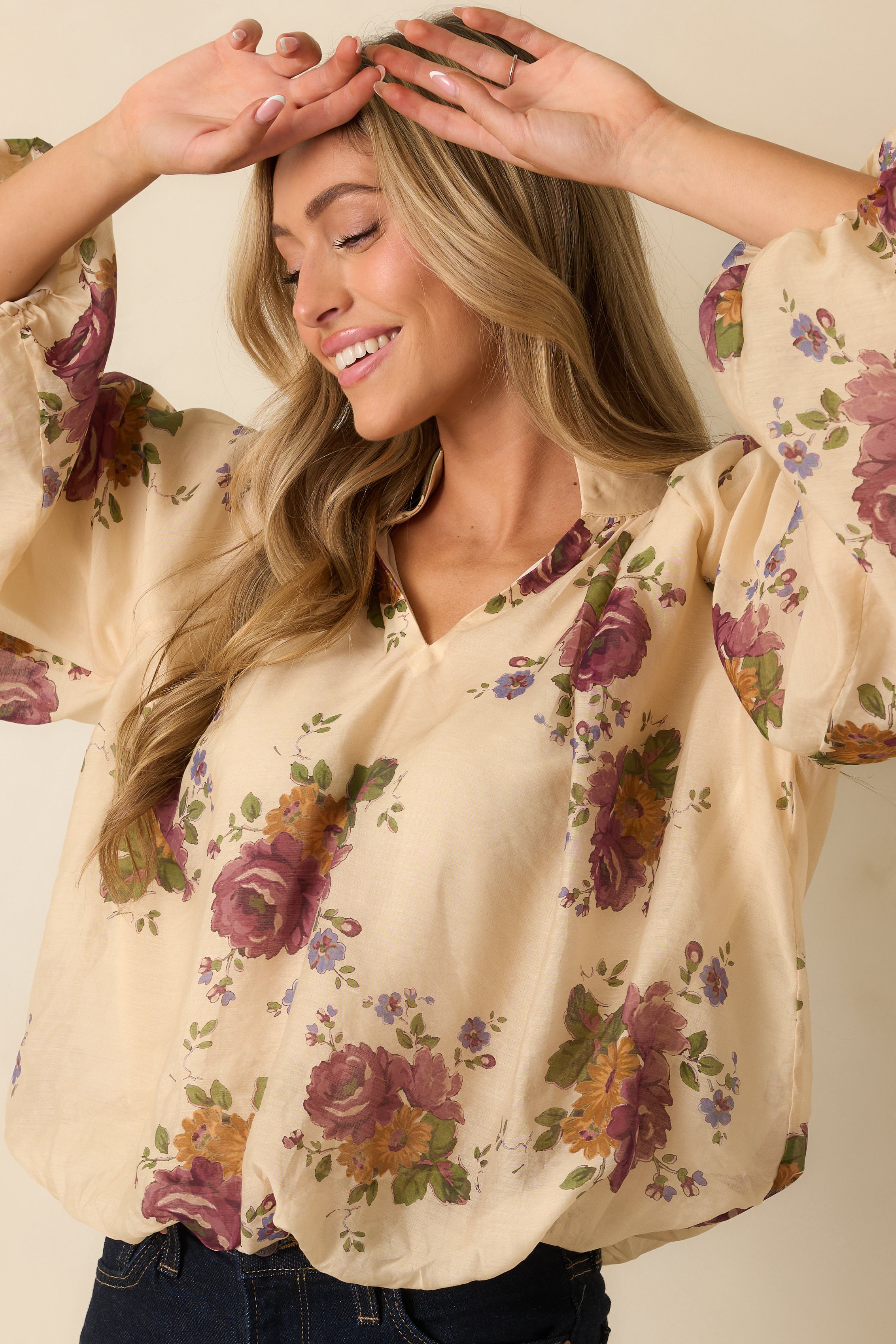 Detailed look at the elastic hemline and relaxed drape of the ivory floral top.