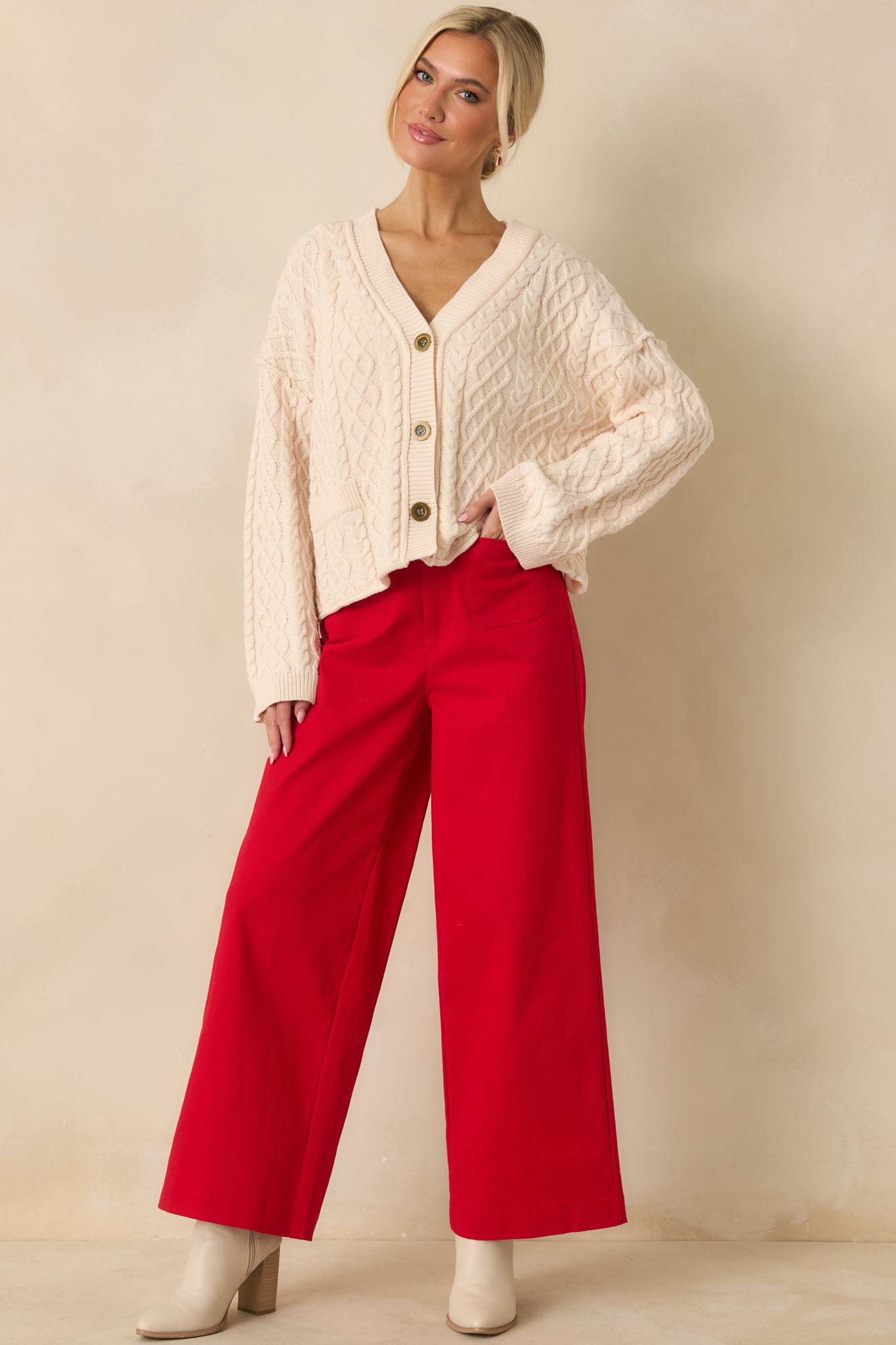 Ivory cardigan displayed from the front highlighting the cable knit texture, long sleeves, and ribbed hem.