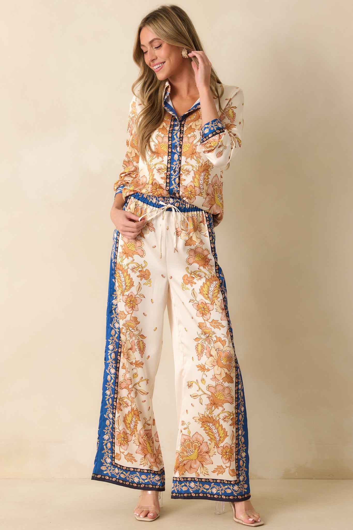 Ivory wide-leg pants with golden yellow floral scarf-style print, contrast navy border trim, and high-rise elastic waistband.