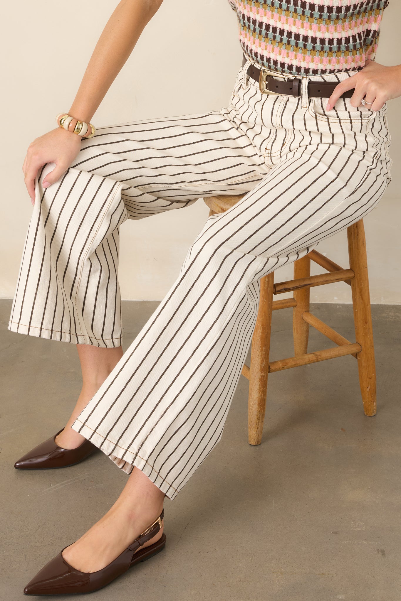 High-rise ivory denim pants detailed with precise brown pinstripes and classic five-pocket styling for a polished finish.