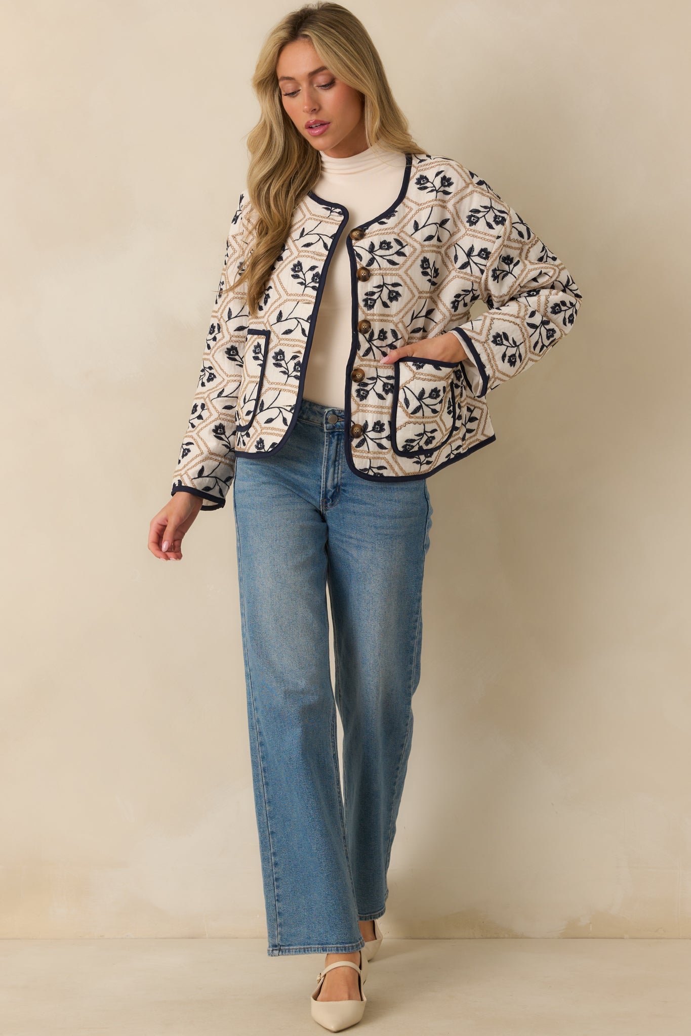 Ivory jacket with tan and navy floral embroidered geometric pattern, round neckline, and long sleeves.