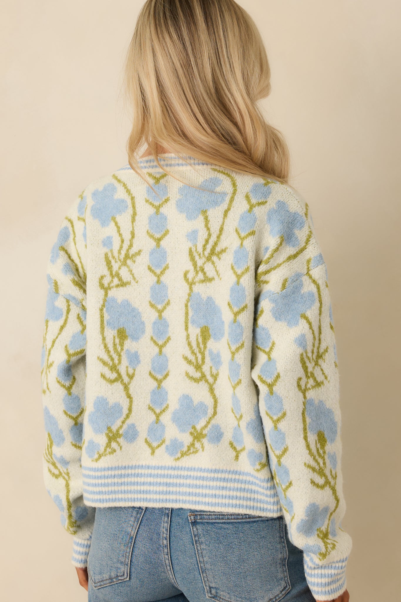 Back view of the ivory knit cardigan showing the allover blue and green floral pattern and relaxed fit.