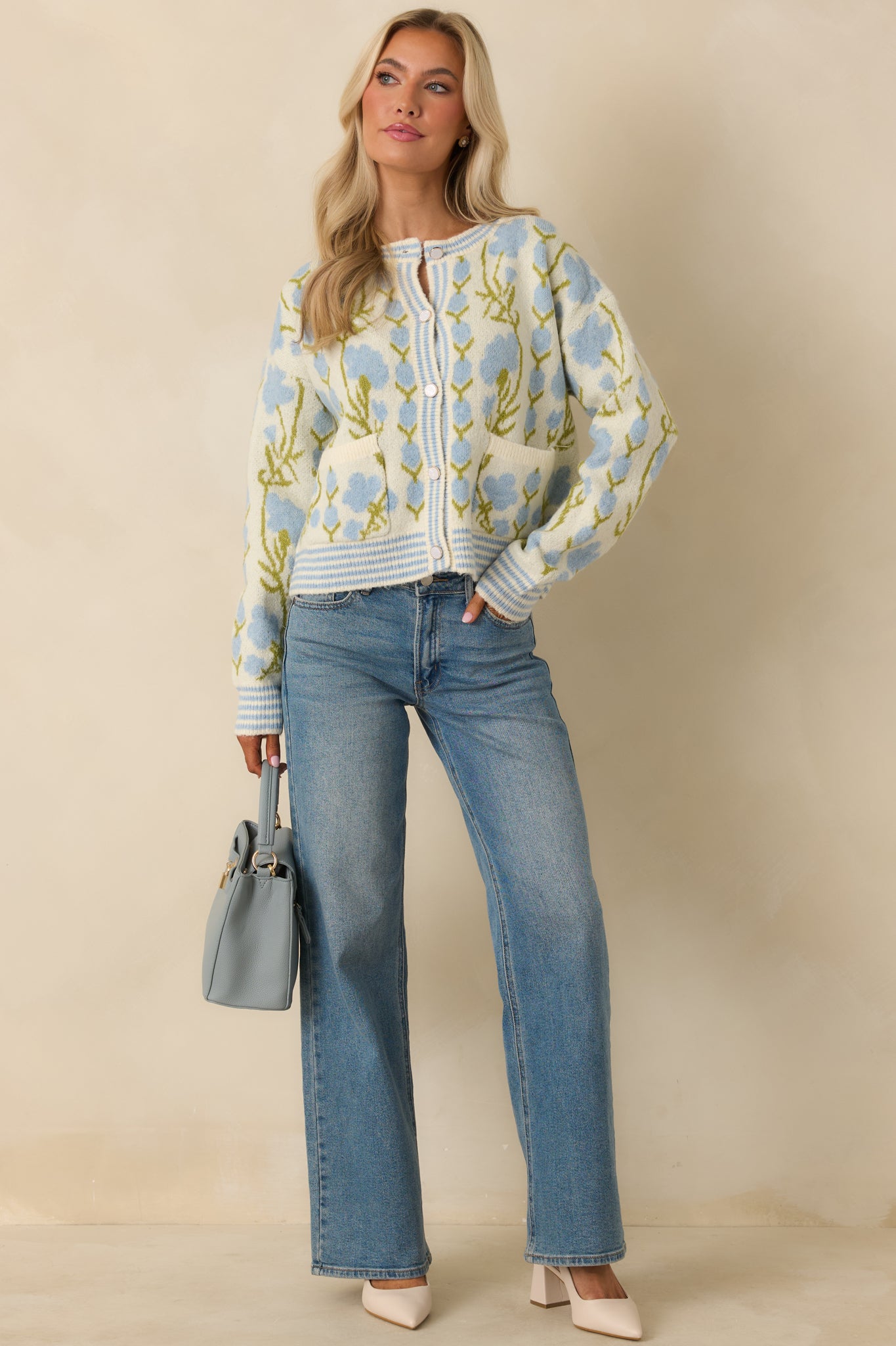 Ivory knit cardigan with blue and green floral pattern, round neckline, and full button-front closure.